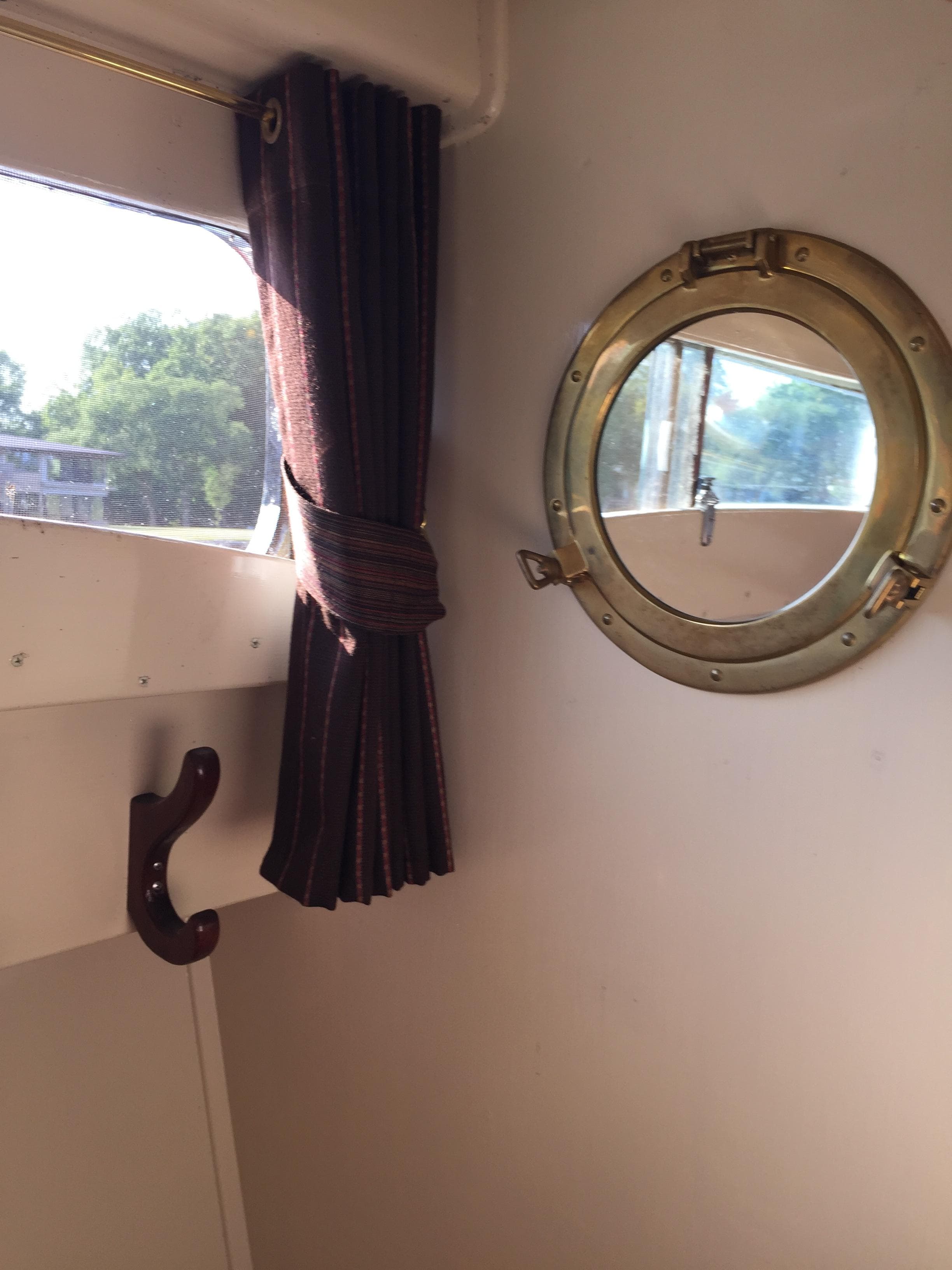 1954 Chris-Craft Commander interior with porthole and window curtain.