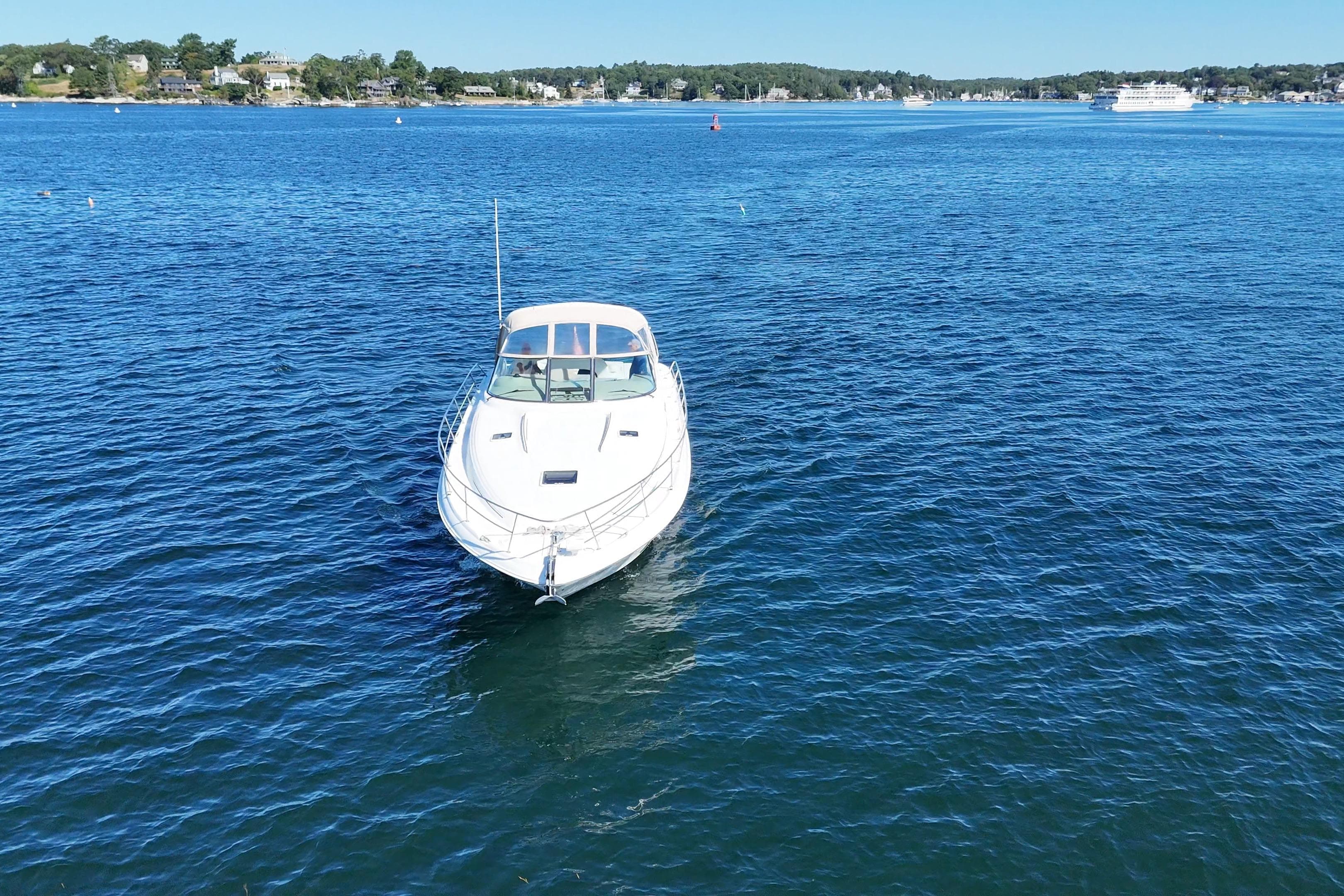 2000 Sea Ray 410 Express Cruiser on calm blue water, distant shoreline visible.