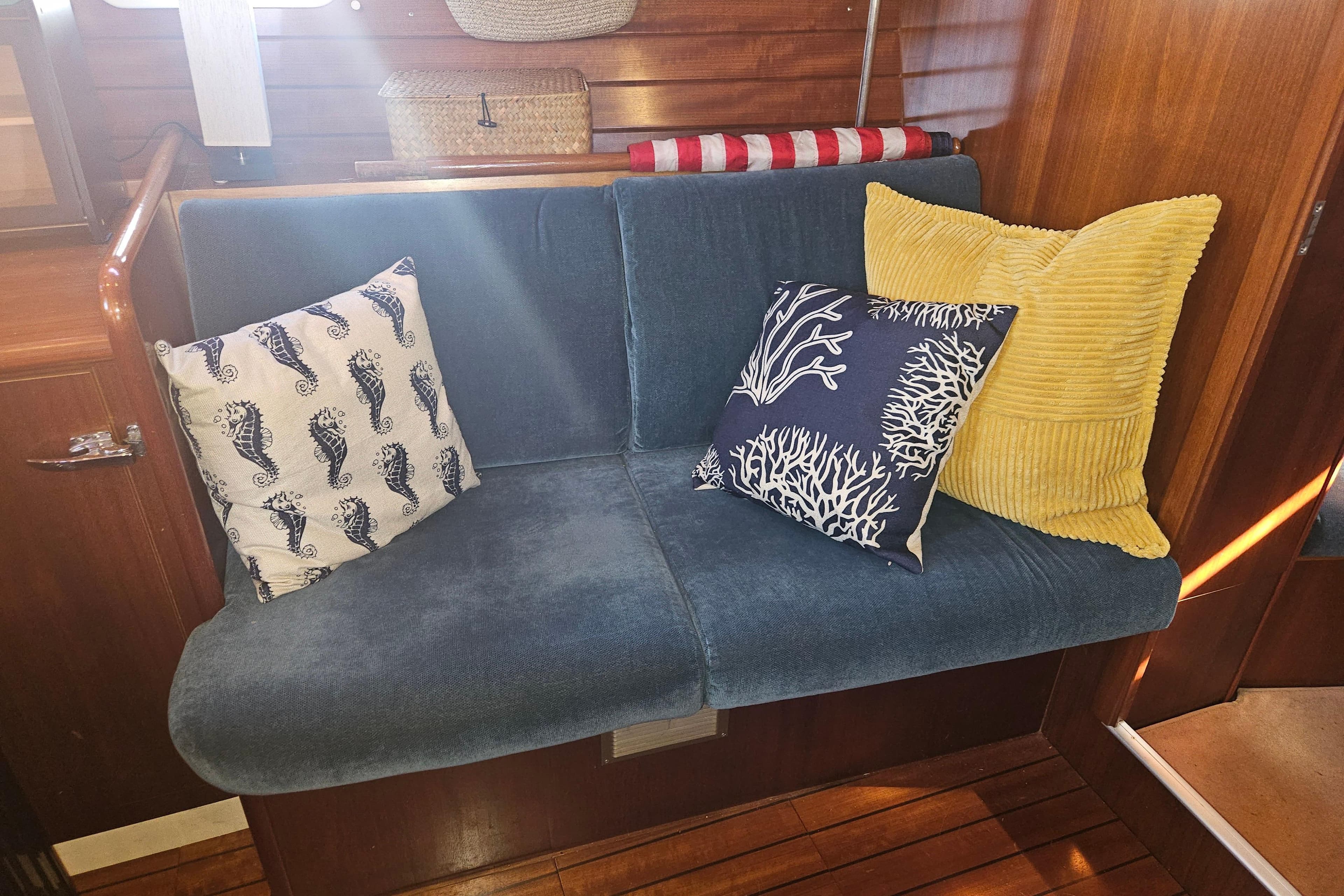 Cozy seating area on a 1998 Beneteau 381 sailboat with decorative pillows.