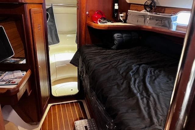 Cozy cabin interior of a 1996 Hunter 430 sailboat with wooden accents and a black bedspread.