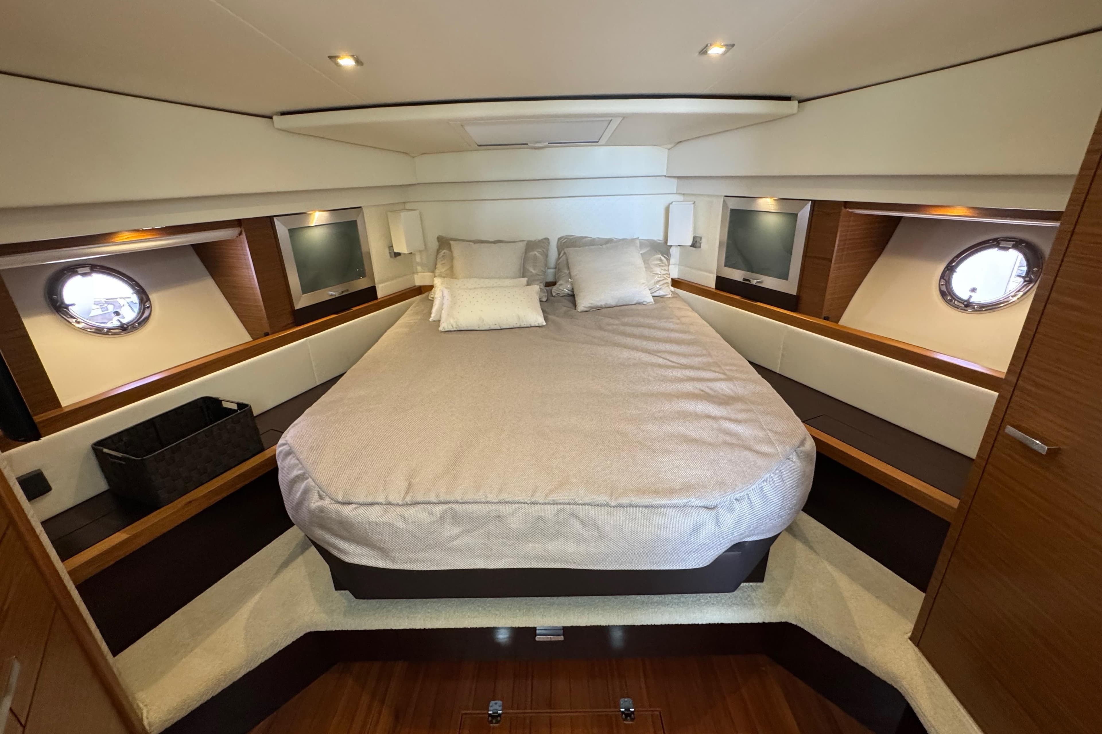 Luxurious bedroom interior of 2018 Tiara Yachts C44 Coupe with elegant bedding and porthole windows.