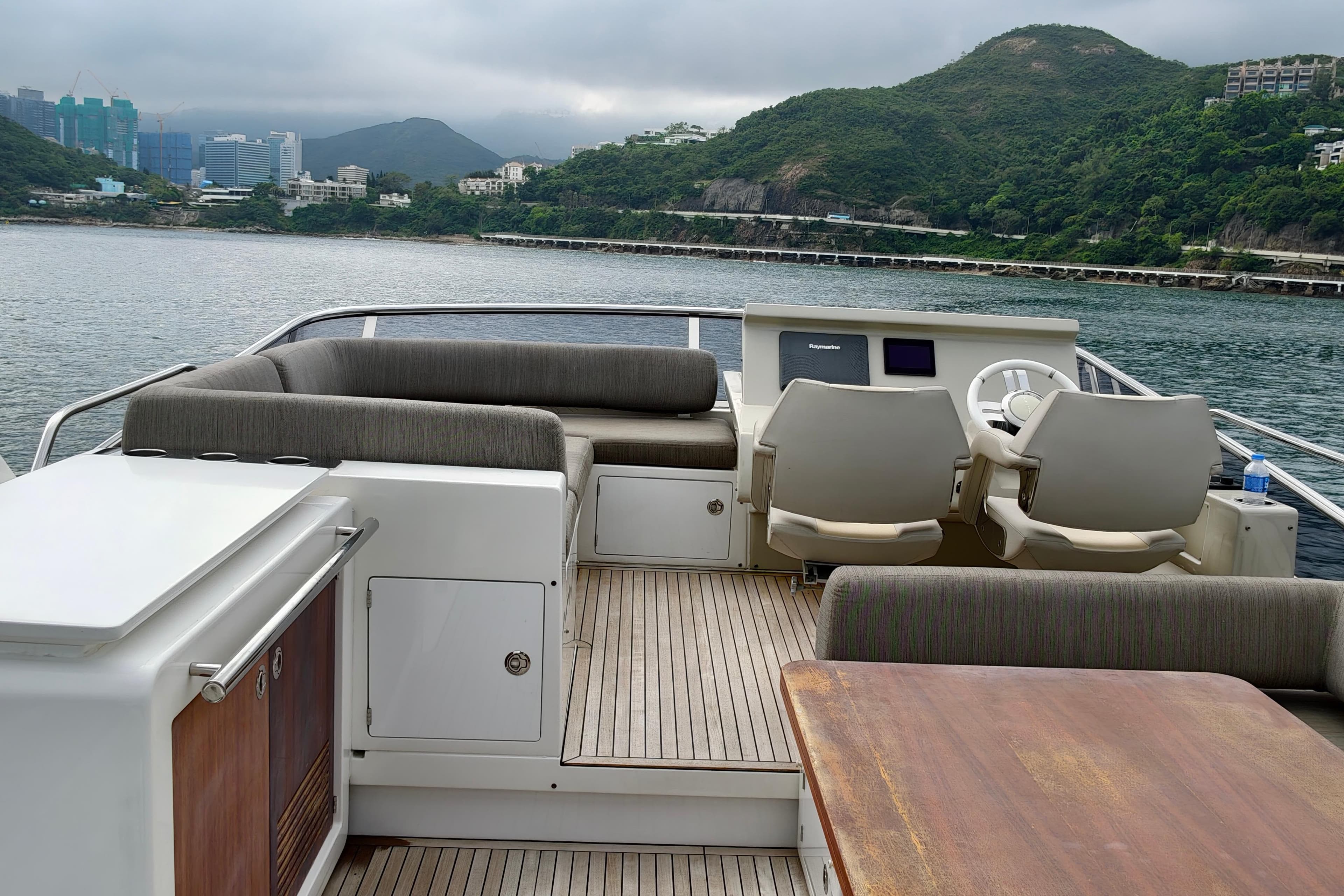 Luxurious 2017 Azimut 66 yacht deck with seating, helm, and scenic waterfront view.