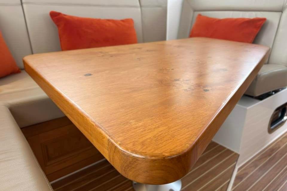 Elegant wooden table with orange cushions in a 2019 Cockwells Duchy 35 yacht interior.