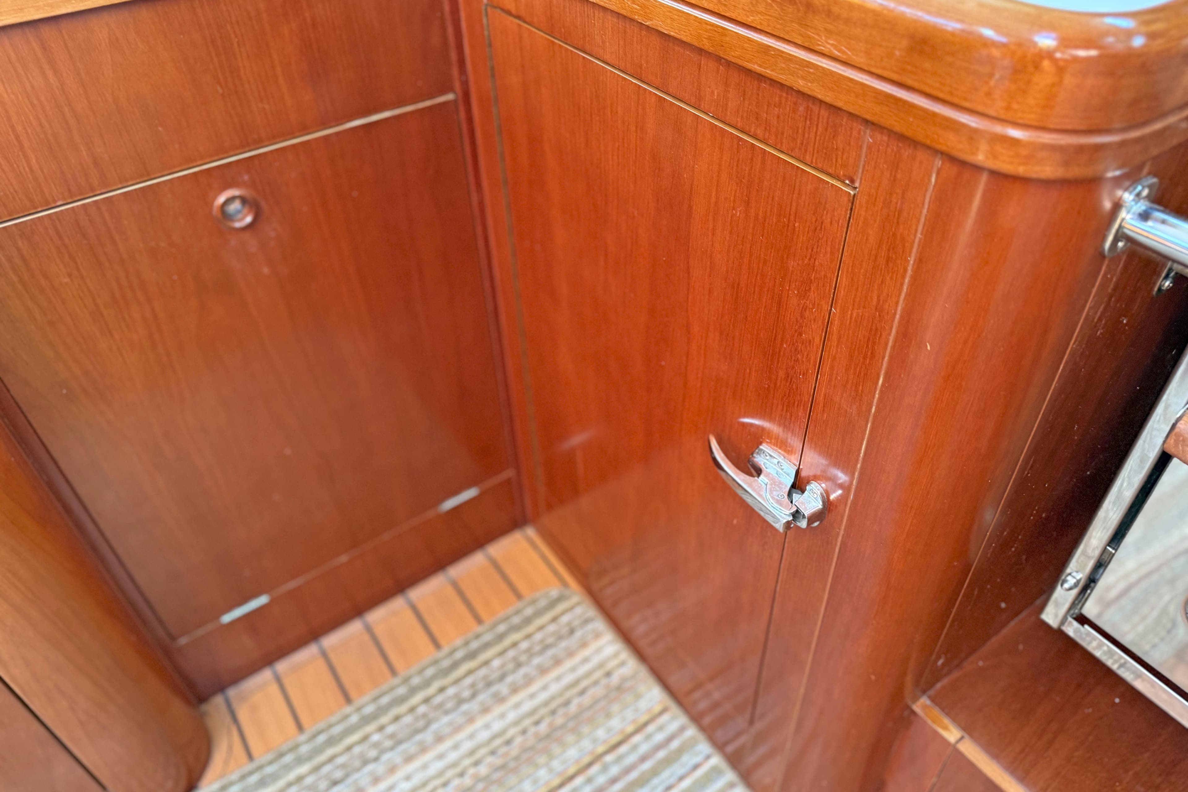 Wooden cabinetry inside a 2004 Beneteau 473 yacht, featuring polished finish and metal handle.