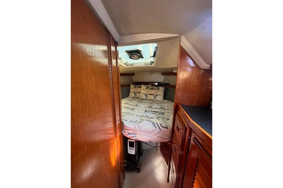 Interior cabin of a 1988 Catalina 30 sailboat with cozy bedding and wooden cabinetry.