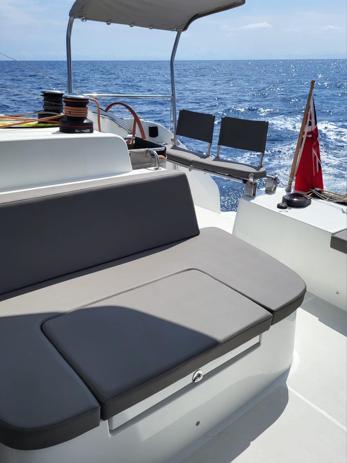 2023 Excess 15 yacht deck with seating, ocean view, and flag.