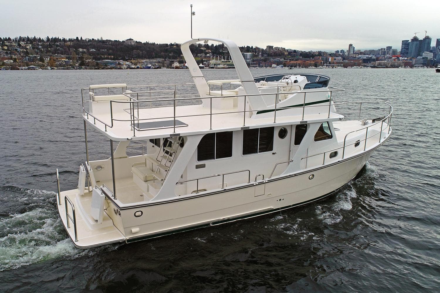 2025 Helmsman Trawlers 38 Sedan cruising on a calm lake with cityscape background.