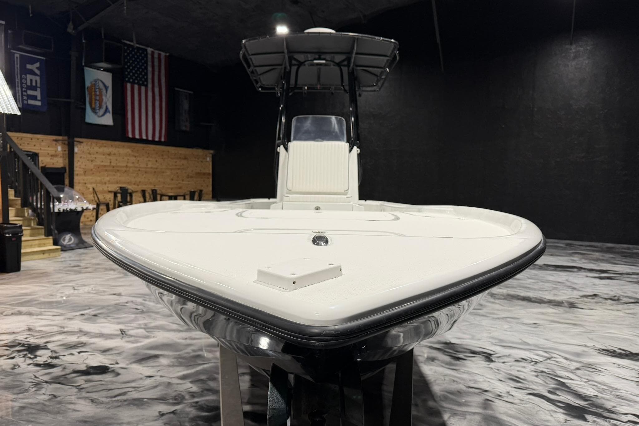 2011 Yellowfin 24 Bay boat in showroom with American flag backdrop.