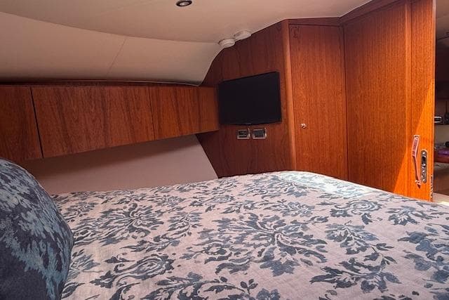 Interior cabin of 2010 Tiara Yachts 3900 Open with wood paneling and patterned bedding.