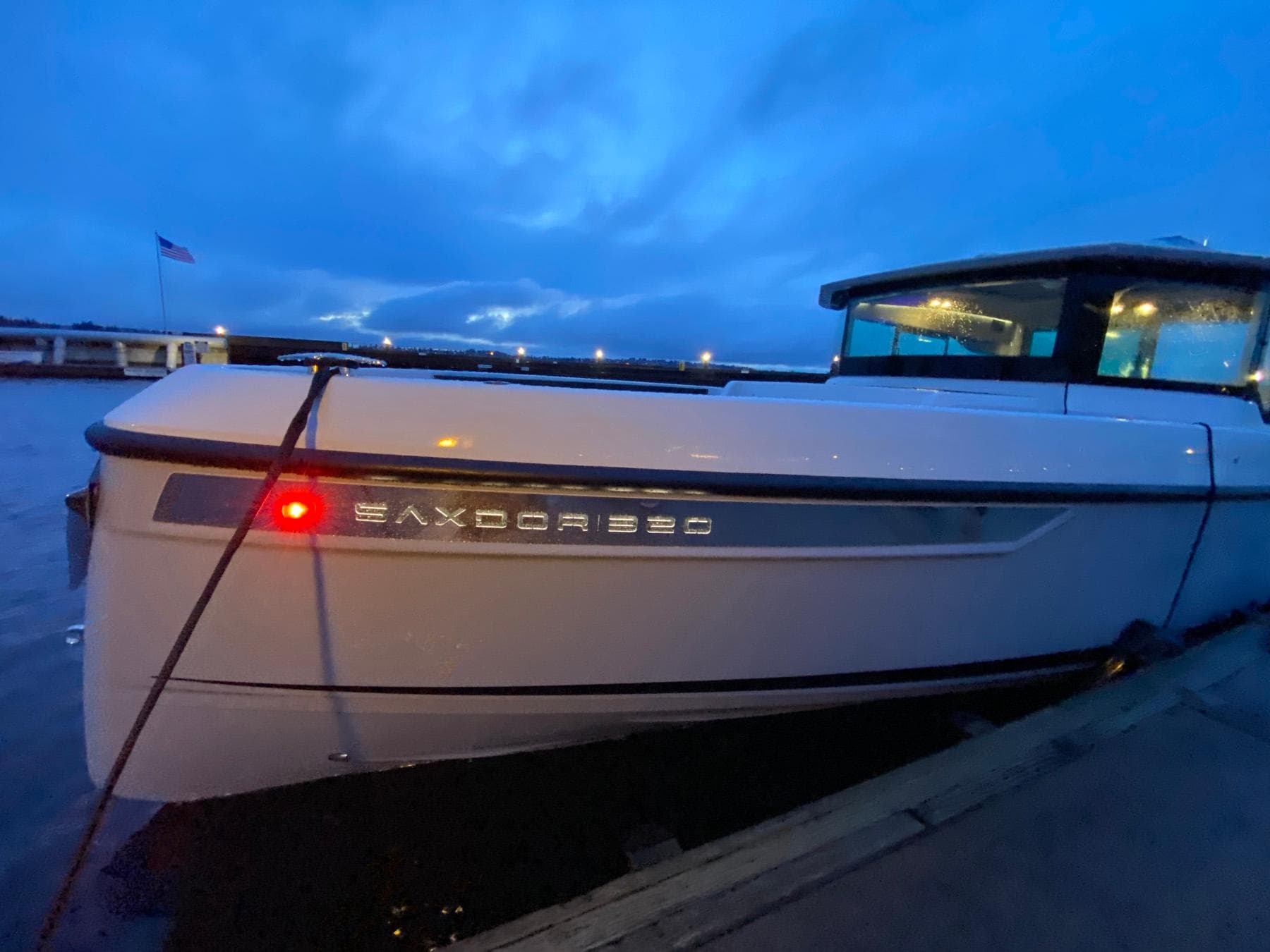2025 Saxdor 320 GTC boat docked at twilight with illuminated nameplate.