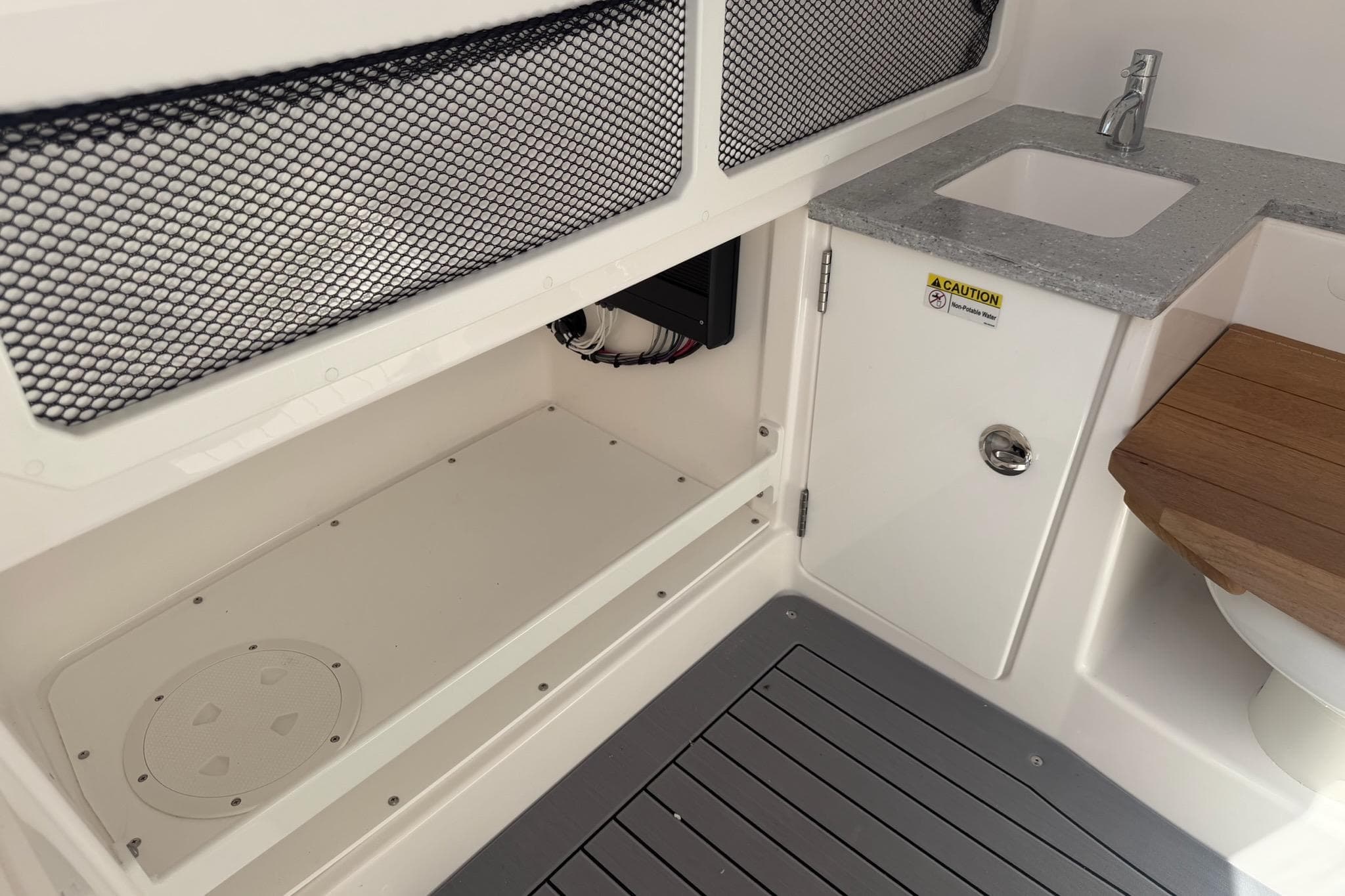 2024 Everglades 335 Center Console interior with sink, storage, and wooden seat.