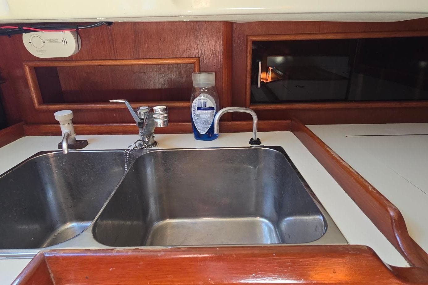 1988 Niagara 35 Encore yacht kitchen sink with wooden cabinetry and cleaning supplies.