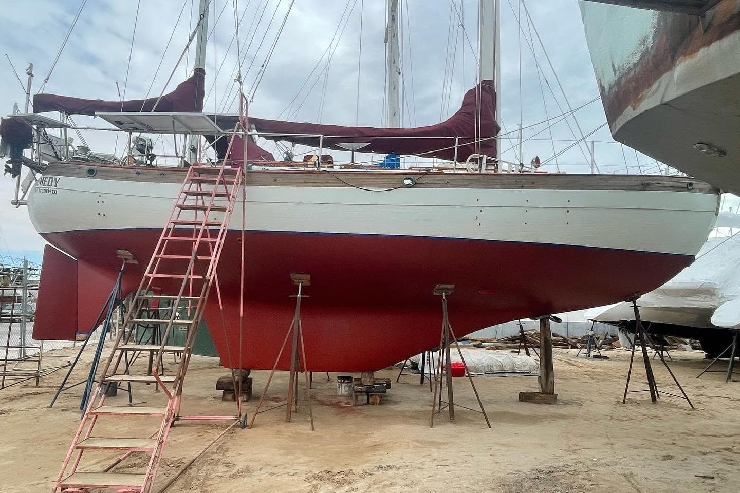 1980 Hans Christian 43 sailboat on dry dock with red hull and maroon covers.