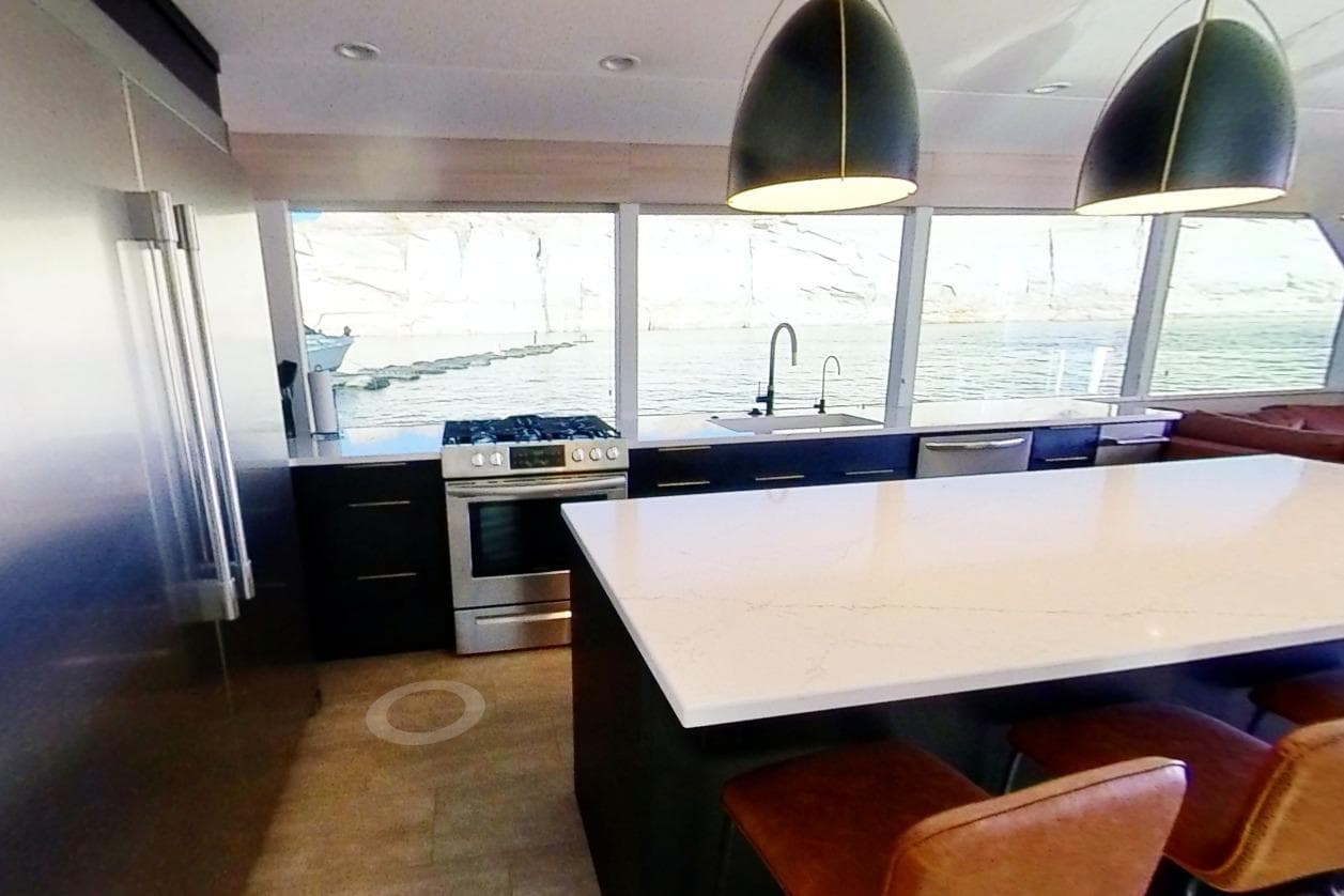 Modern kitchen in 2022 Adonia Splendor houseboat with large island, pendant lights, and scenic window views.