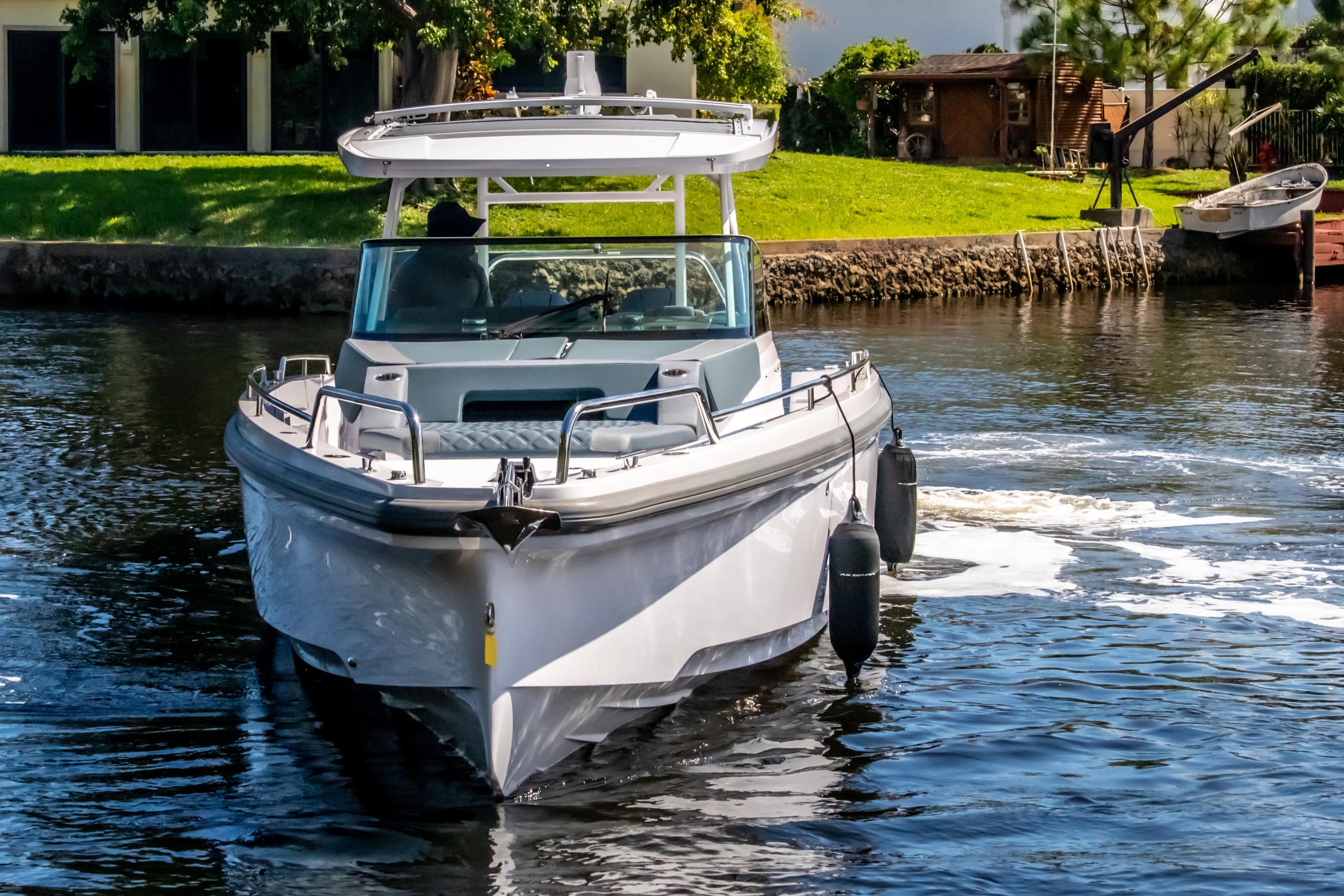 2024 Axopar 37 Sun Top cruising on a calm river, surrounded by greenery.