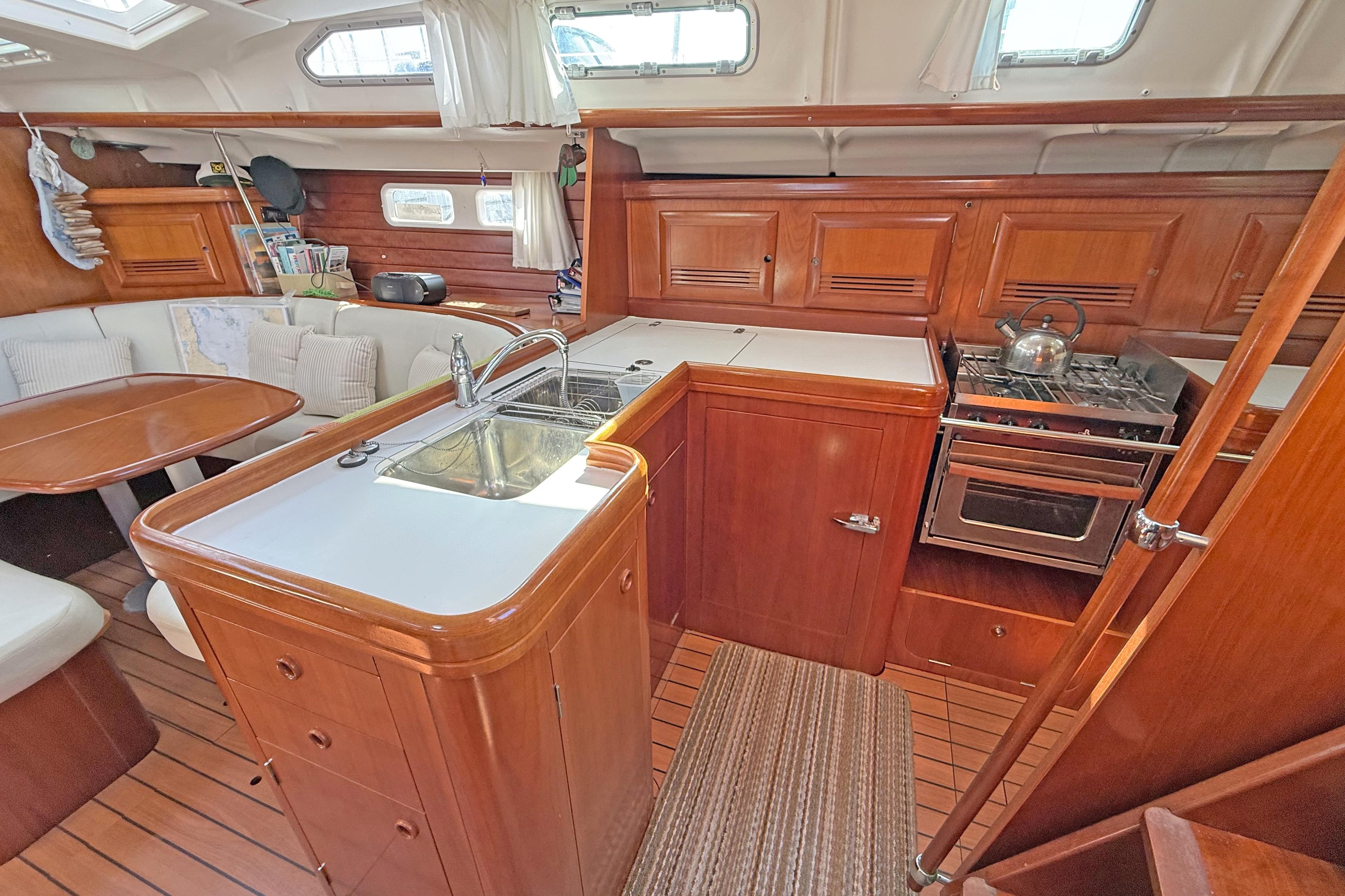 Interior of 2004 Beneteau 473 yacht with wooden cabinetry and compact kitchen area.