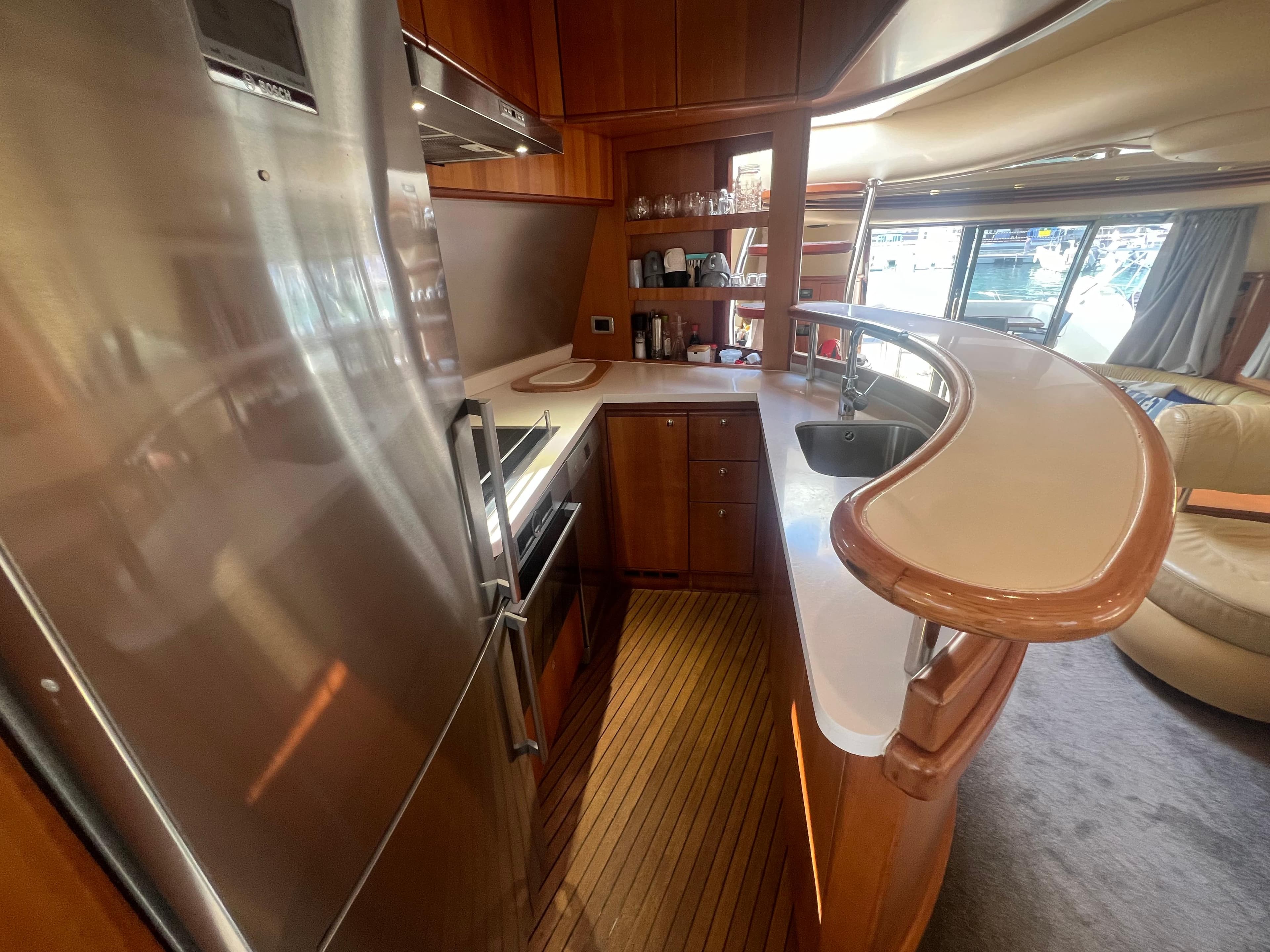 Luxurious kitchen interior of 2007 Azimut 68E yacht with modern appliances and wood finish.