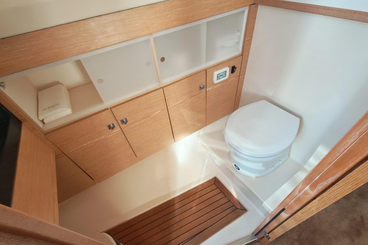 Modern bathroom interior on 2015 Fjord 40 Open yacht, featuring wooden cabinetry and compact toilet.