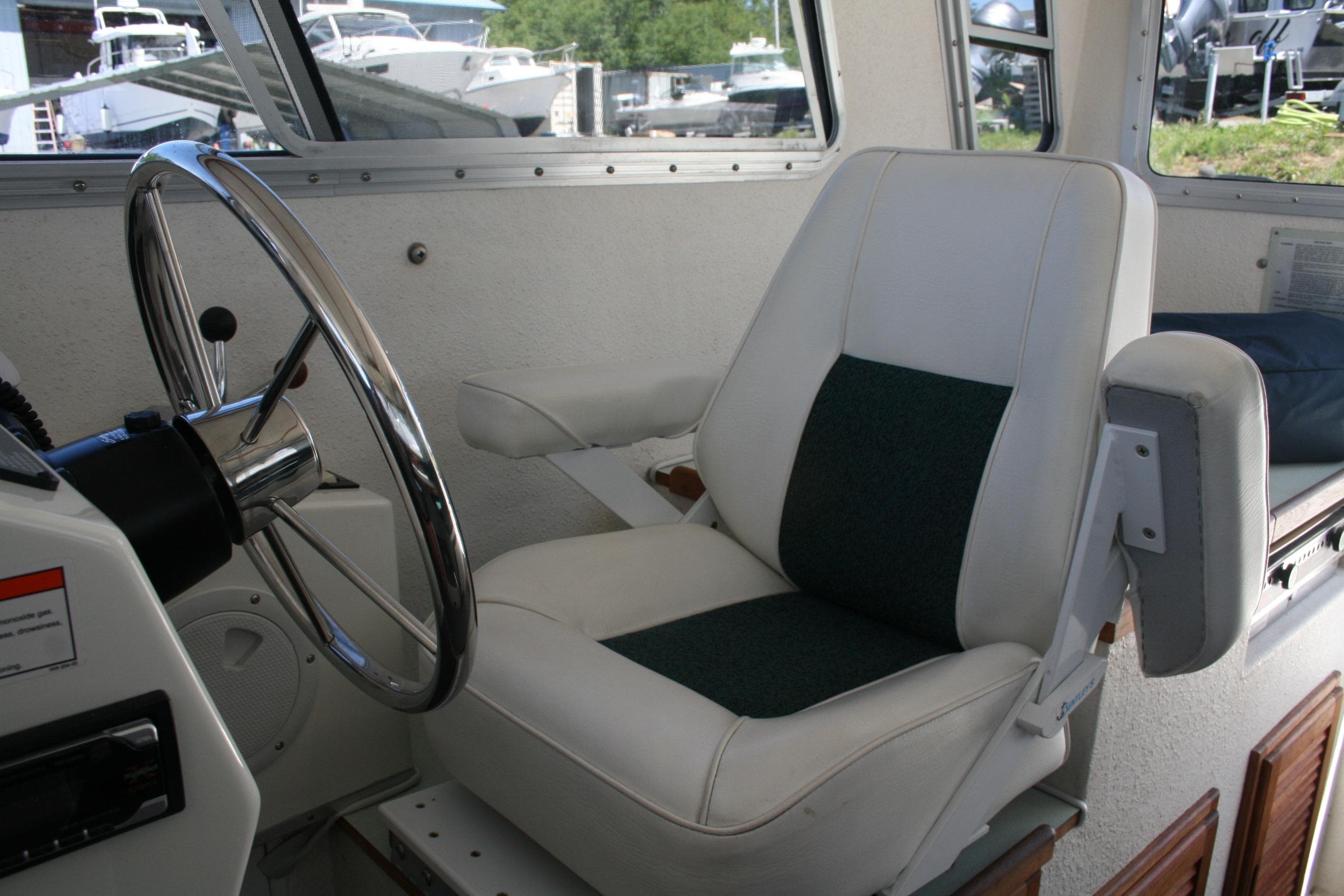 Captain's chair and steering wheel inside a 2002 Sea Sport Explorer 2400 boat.