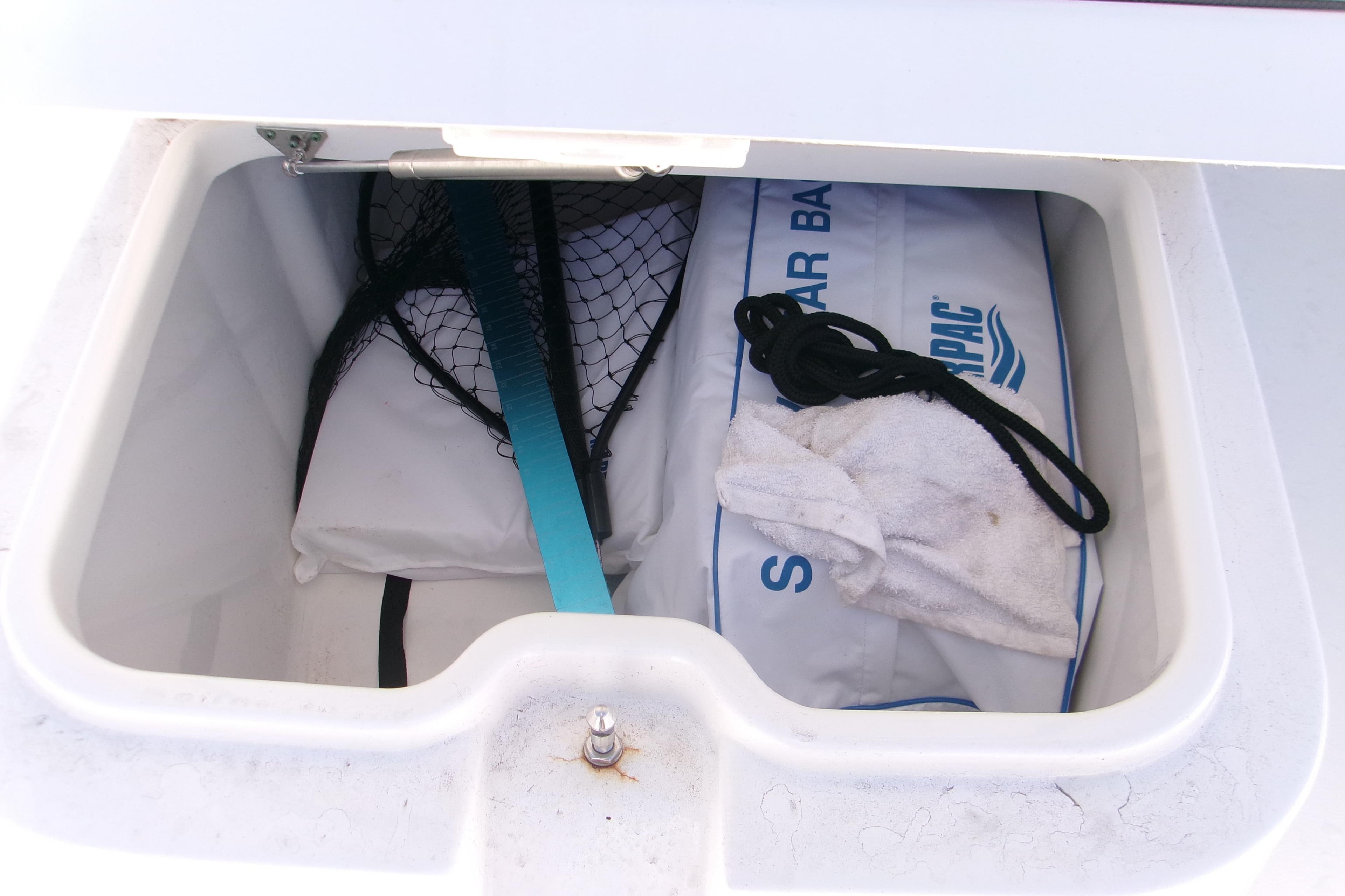Storage compartment in 2024 Sportsman Masters 267OE Bay Boat with fishing gear and accessories.