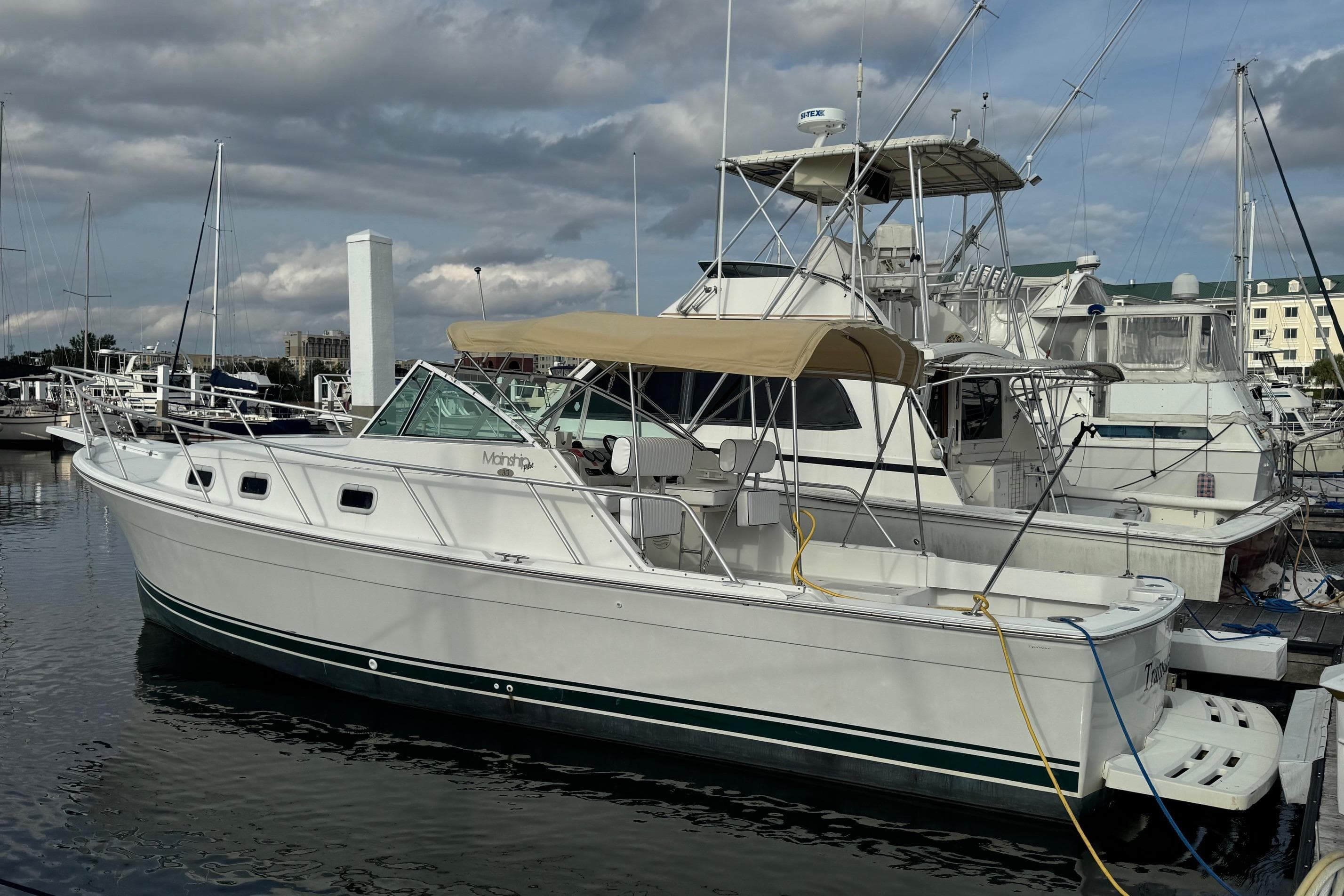 2000 Mainship Pilot 30 docked at marina under cloudy sky.
