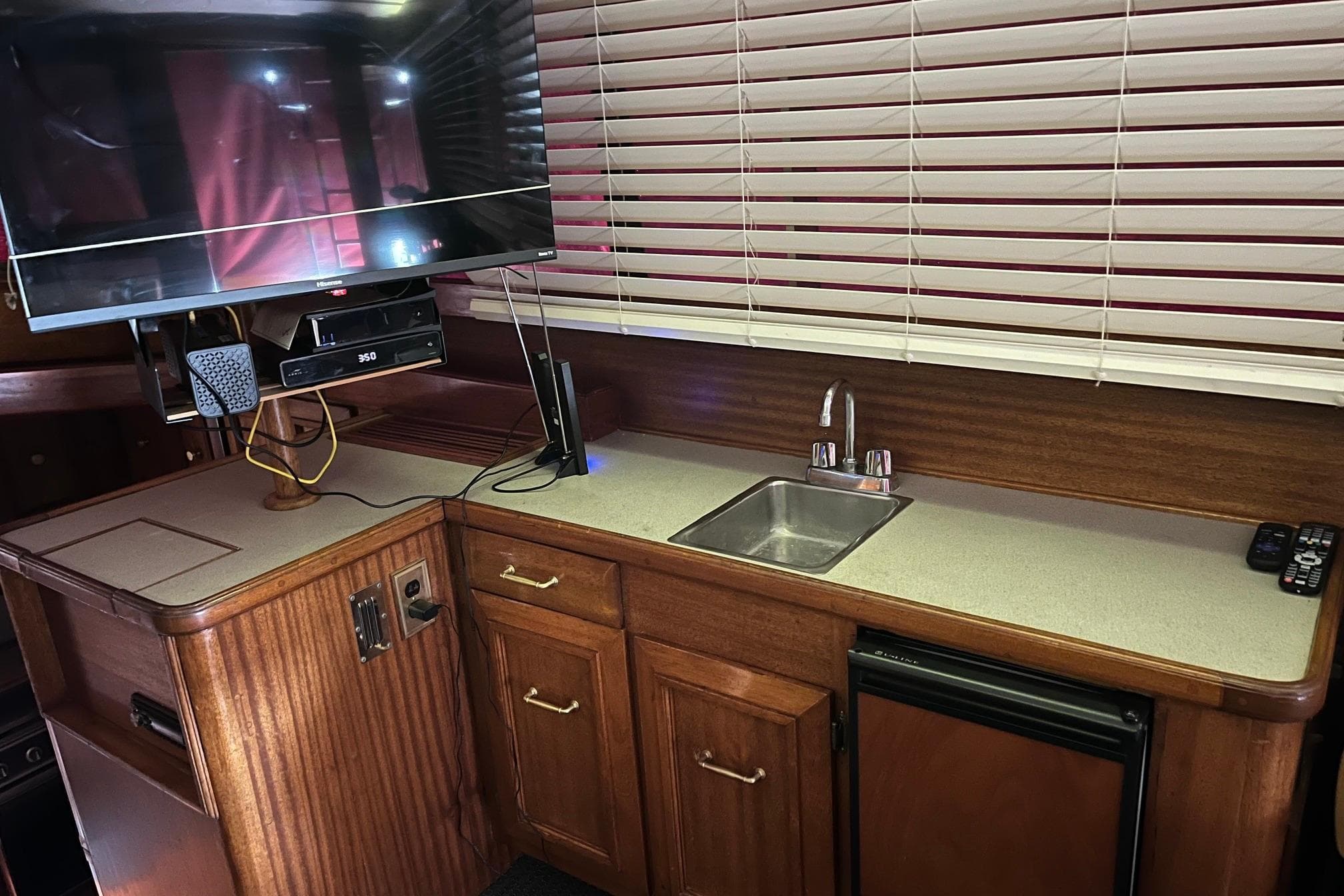 Interior of 1980 Egg Harbor 52 Convertible yacht with kitchenette, sink, and mounted TV.