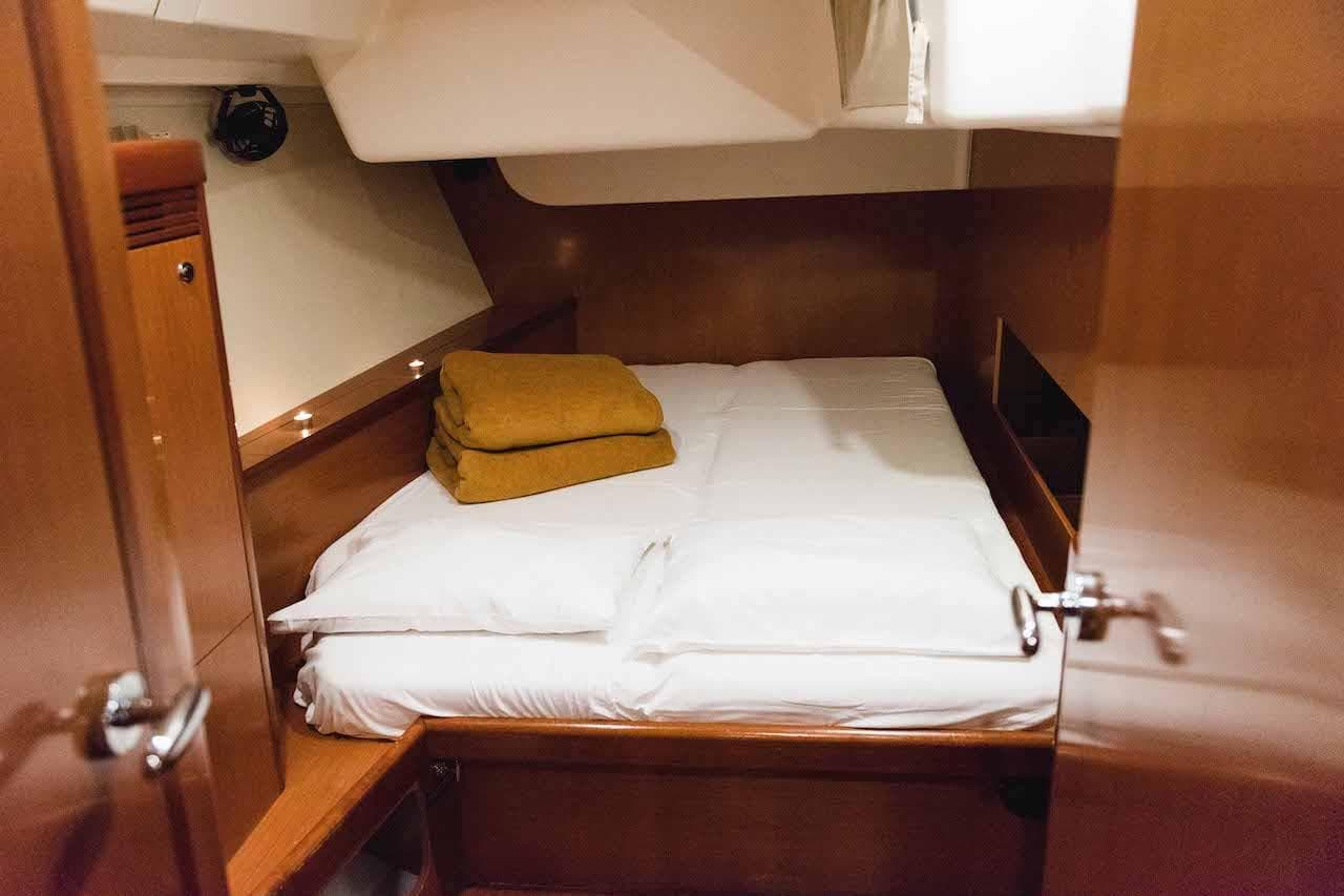 Cozy cabin interior of 2009 Beneteau Oceanis 54 yacht with neatly arranged bedding.