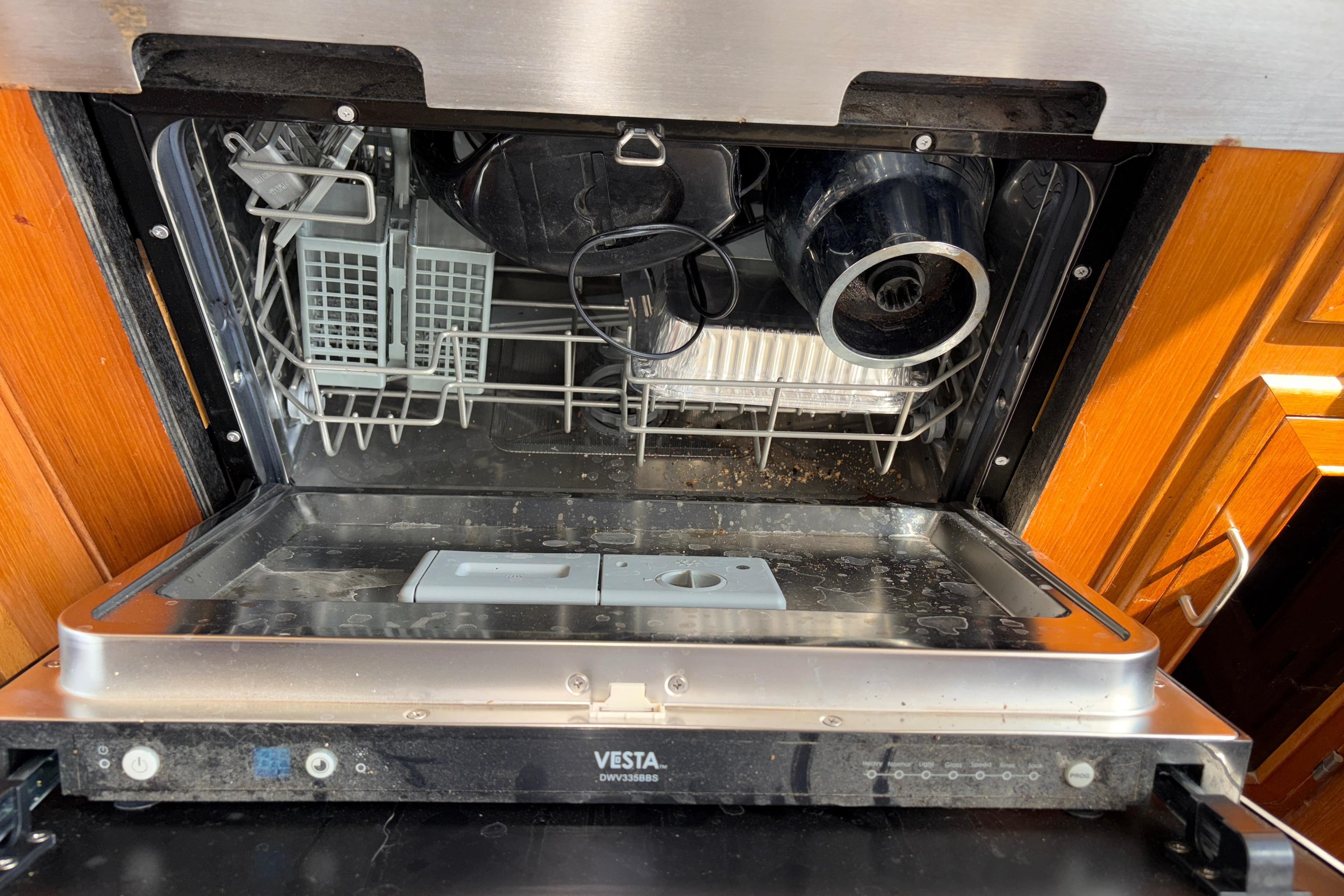 Open Vesta dishwasher with dishes inside, wooden cabinetry, Angel Pilothouse 1990 model.