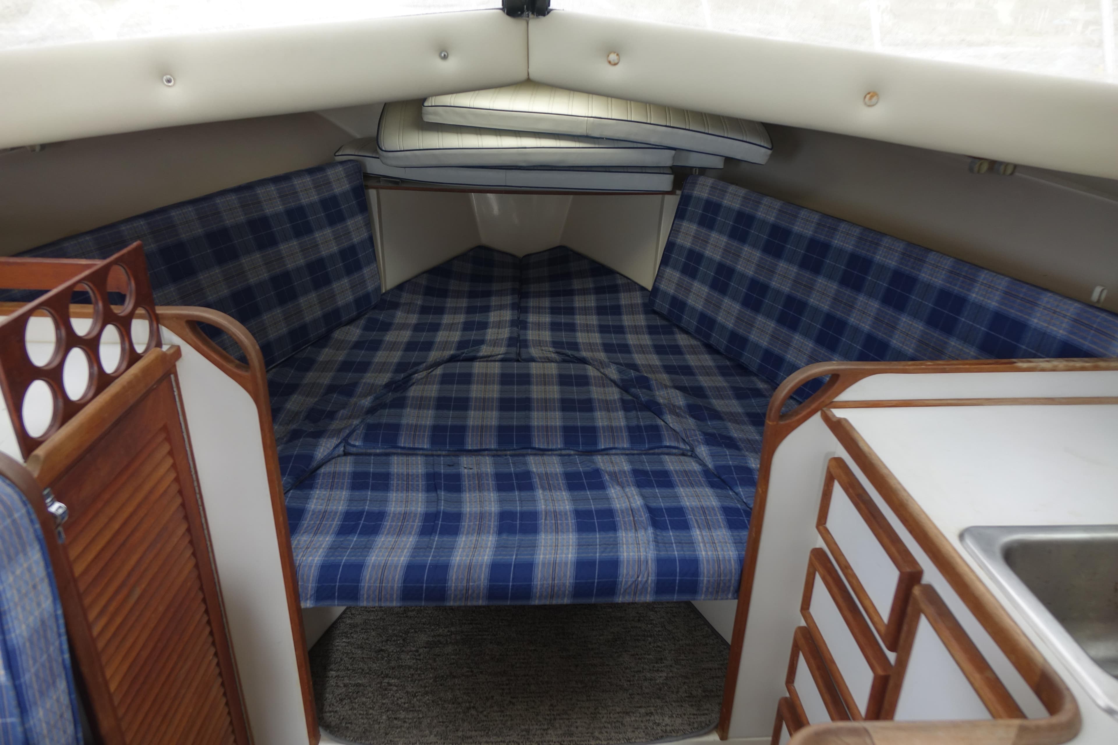 1988 Blackfin 29 Flybridge cabin interior with blue plaid upholstery and wooden cabinetry.