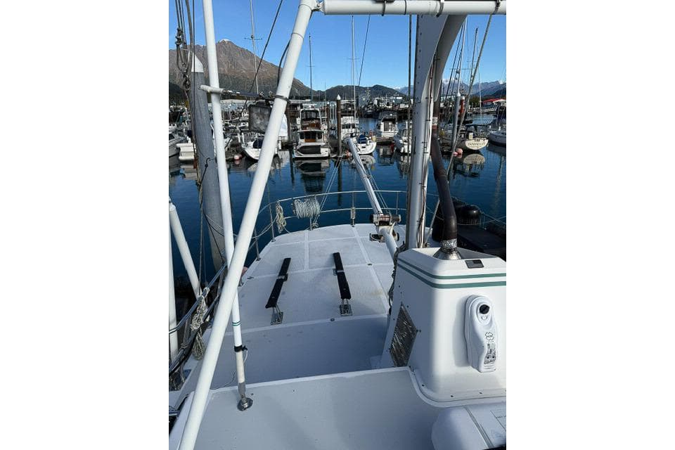 Nordhavn 46 yacht deck view in marina, showcasing boats and mountains in the background.