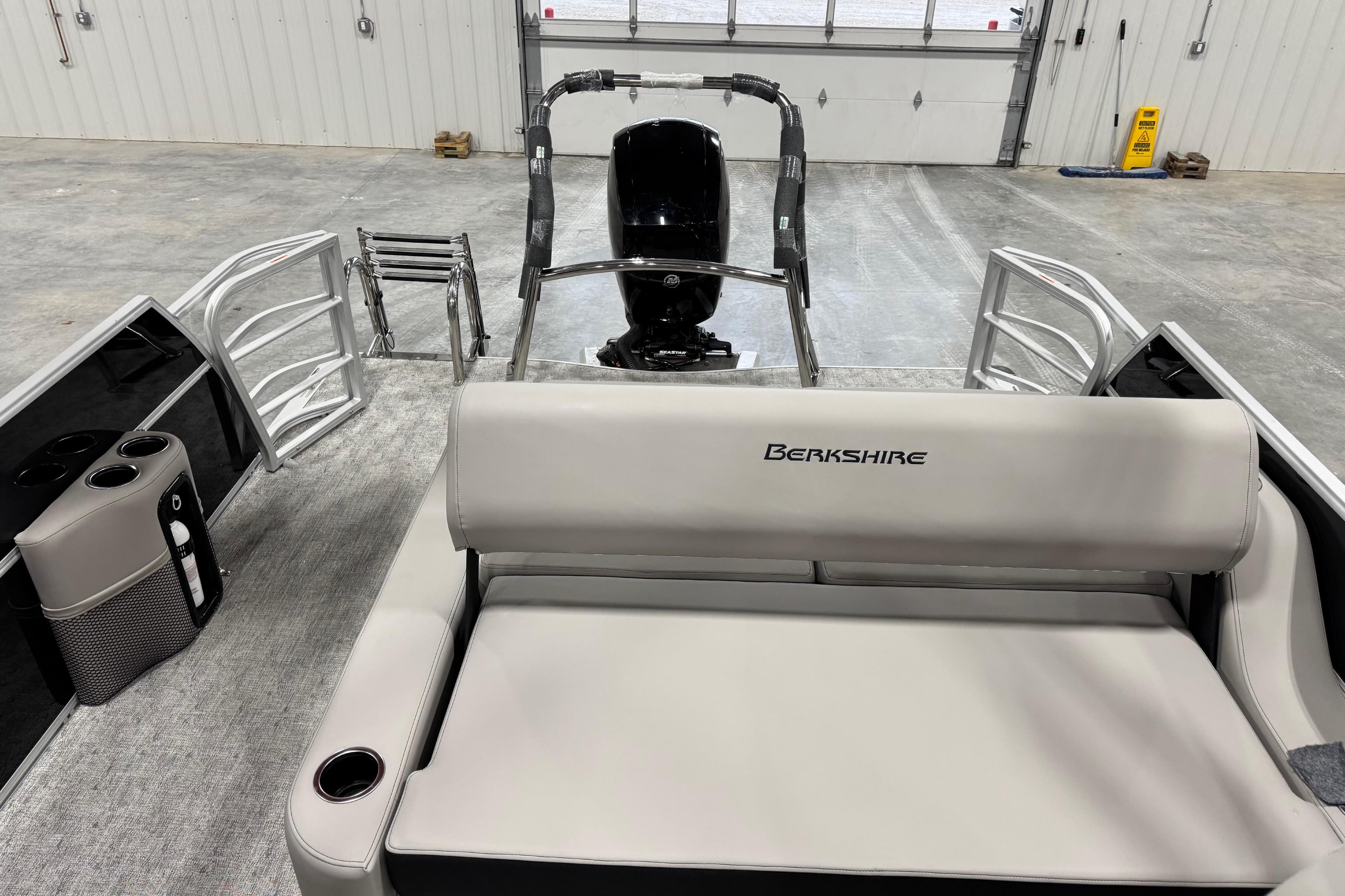 2026 Berkshire 24 UL LE pontoon boat interior with seating and motor in a garage.