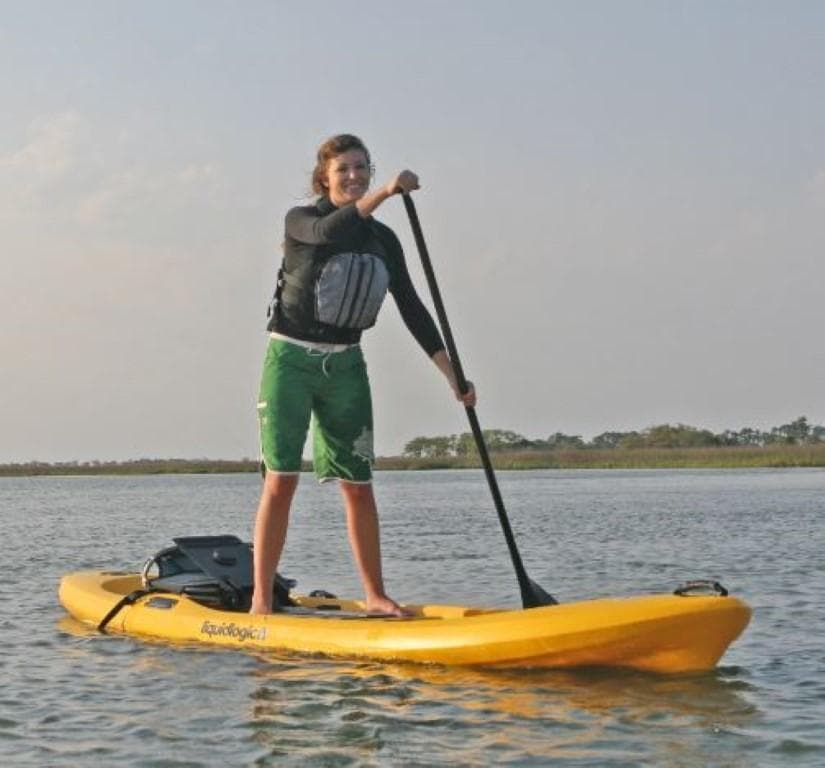 Person paddleboarding on a 2023 Liquidlogic Versa Board in calm waters.