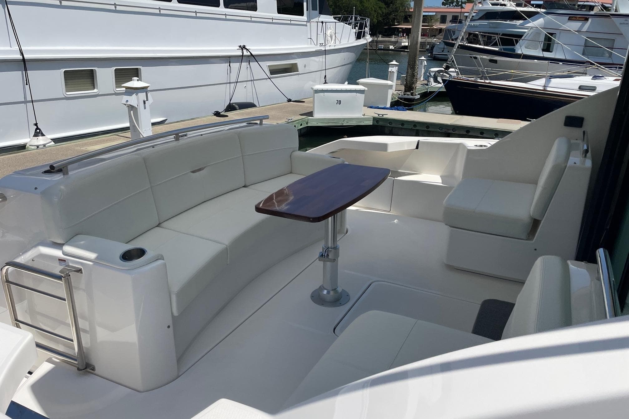 2023 Tiara Yachts C44 Coupe cockpit with white seating and wooden table at marina.