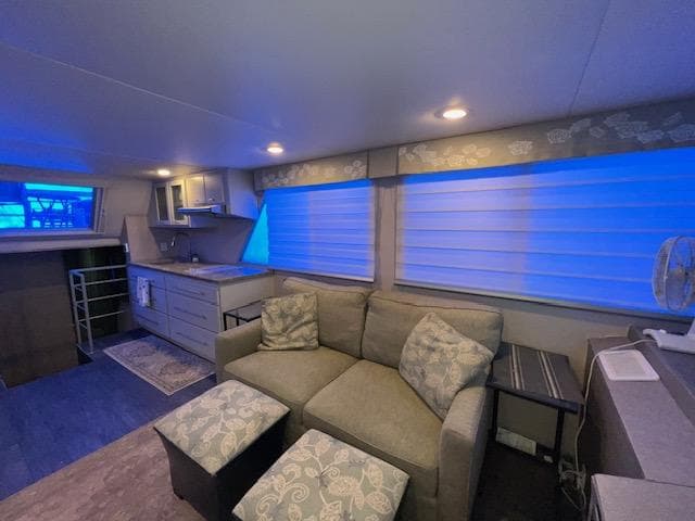 Cozy 1977 Gibson Standard boat interior with sofa, kitchenette, and blue-lit windows.