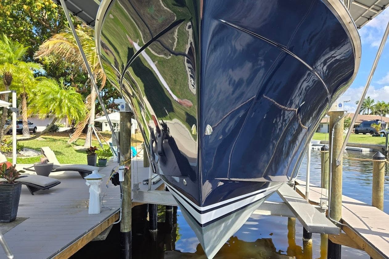 2009 Mainship Pilot 31 boat docked, reflecting sunlight, surrounded by tropical greenery.