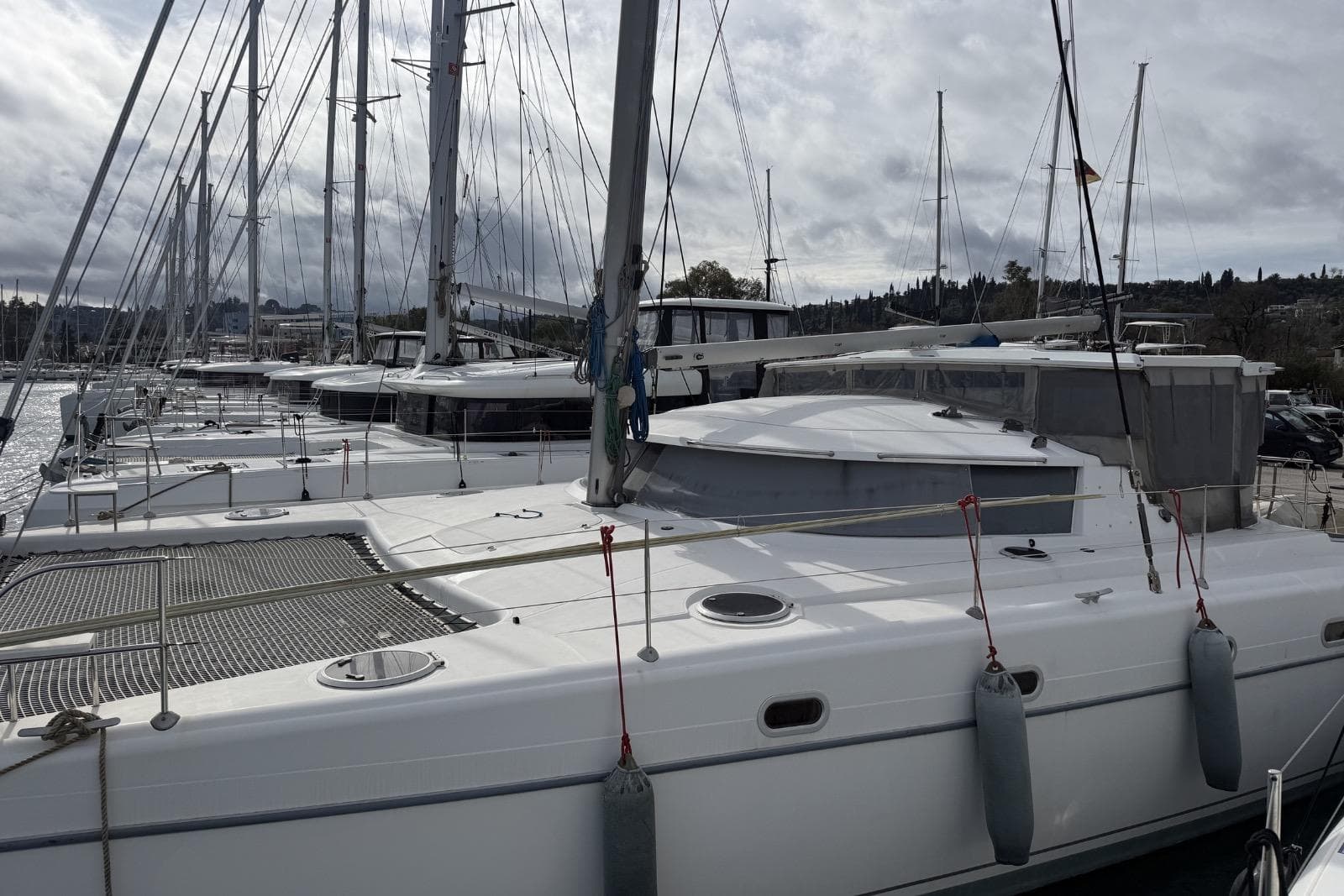 2003 Fountaine Pajot Belize 43 catamaran docked in a marina, surrounded by sailboats.
