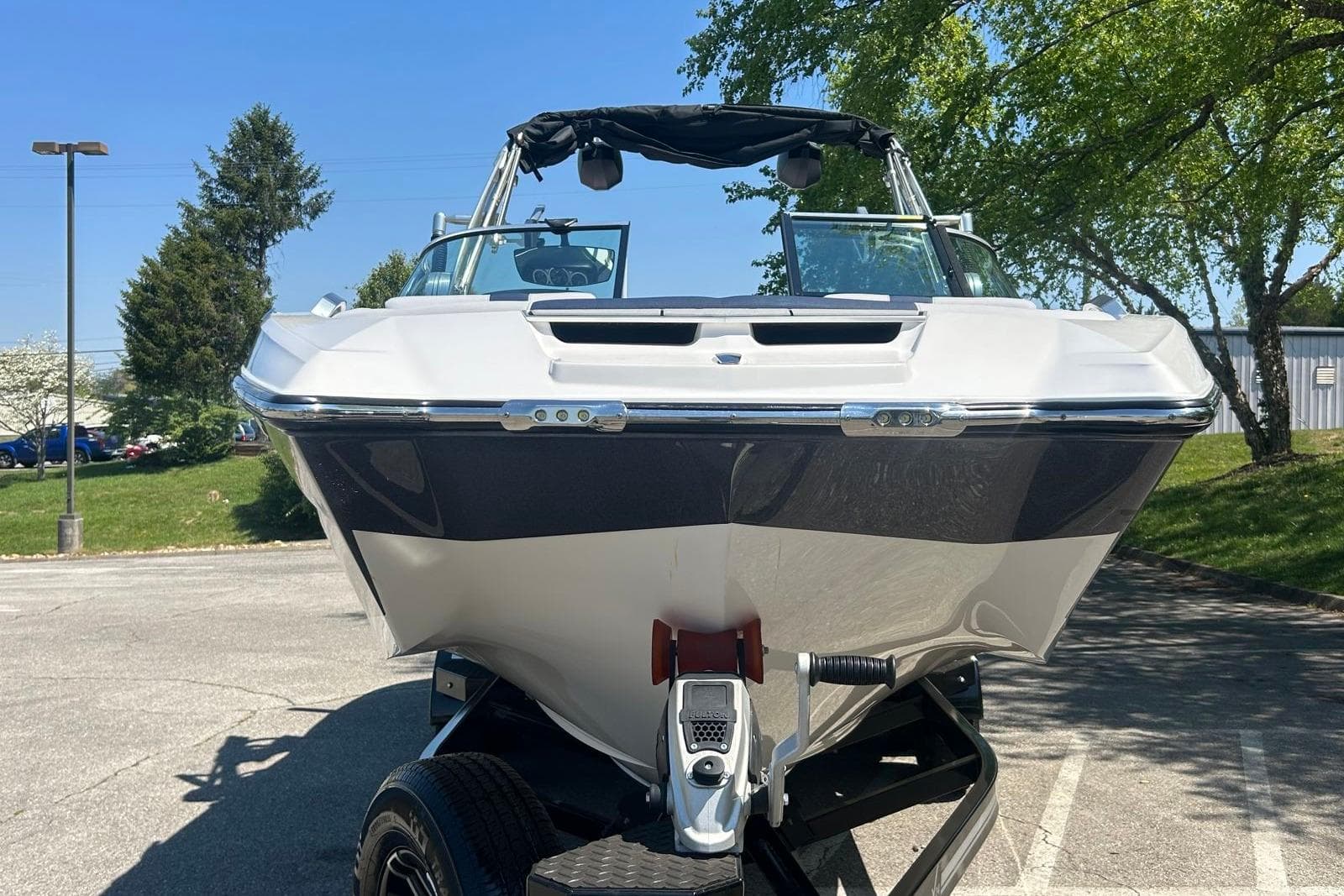 2021 MasterCraft X24 boat on trailer, parked outdoors under clear blue sky.