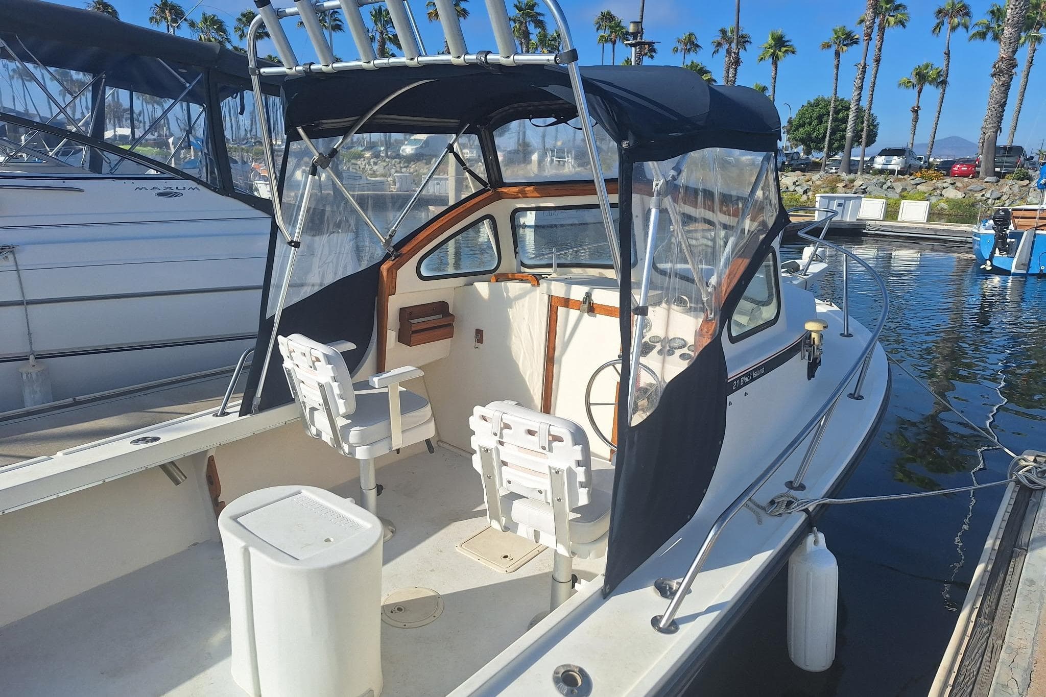 1997 Steiger Craft 21 Block Island boat docked, featuring seating and canopy, with palm trees in background.