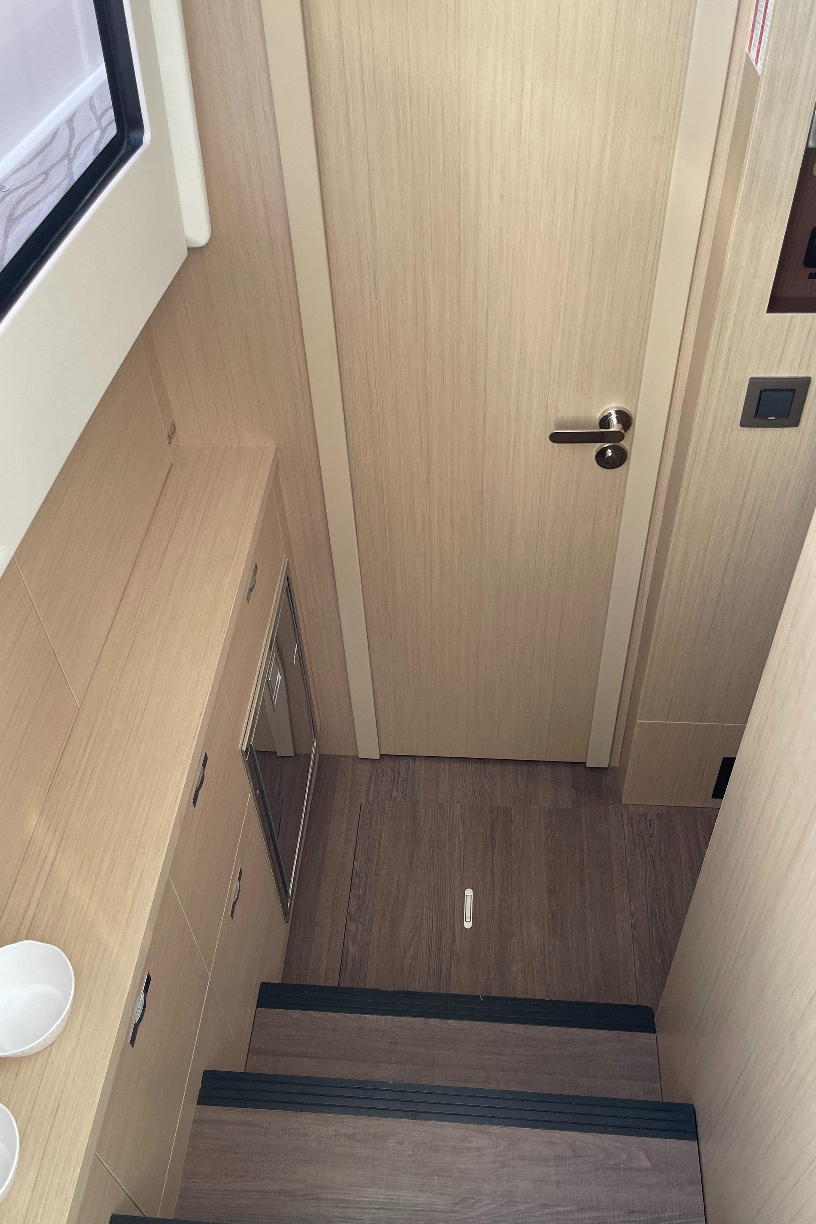 Interior of 2025 Jeanneau DB/37 OB yacht with wooden stairs and door.