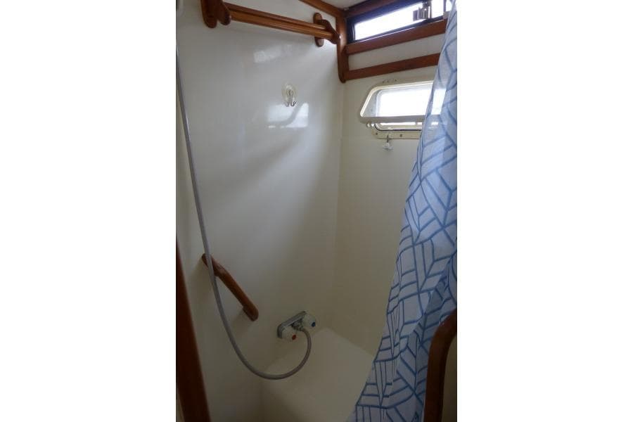 1987 President 37 Aft Cabin shower with curtain and wooden accents.