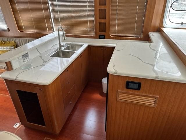 Modern kitchen in 2025 Bracewell 41 yacht with sleek countertops and wooden cabinetry.