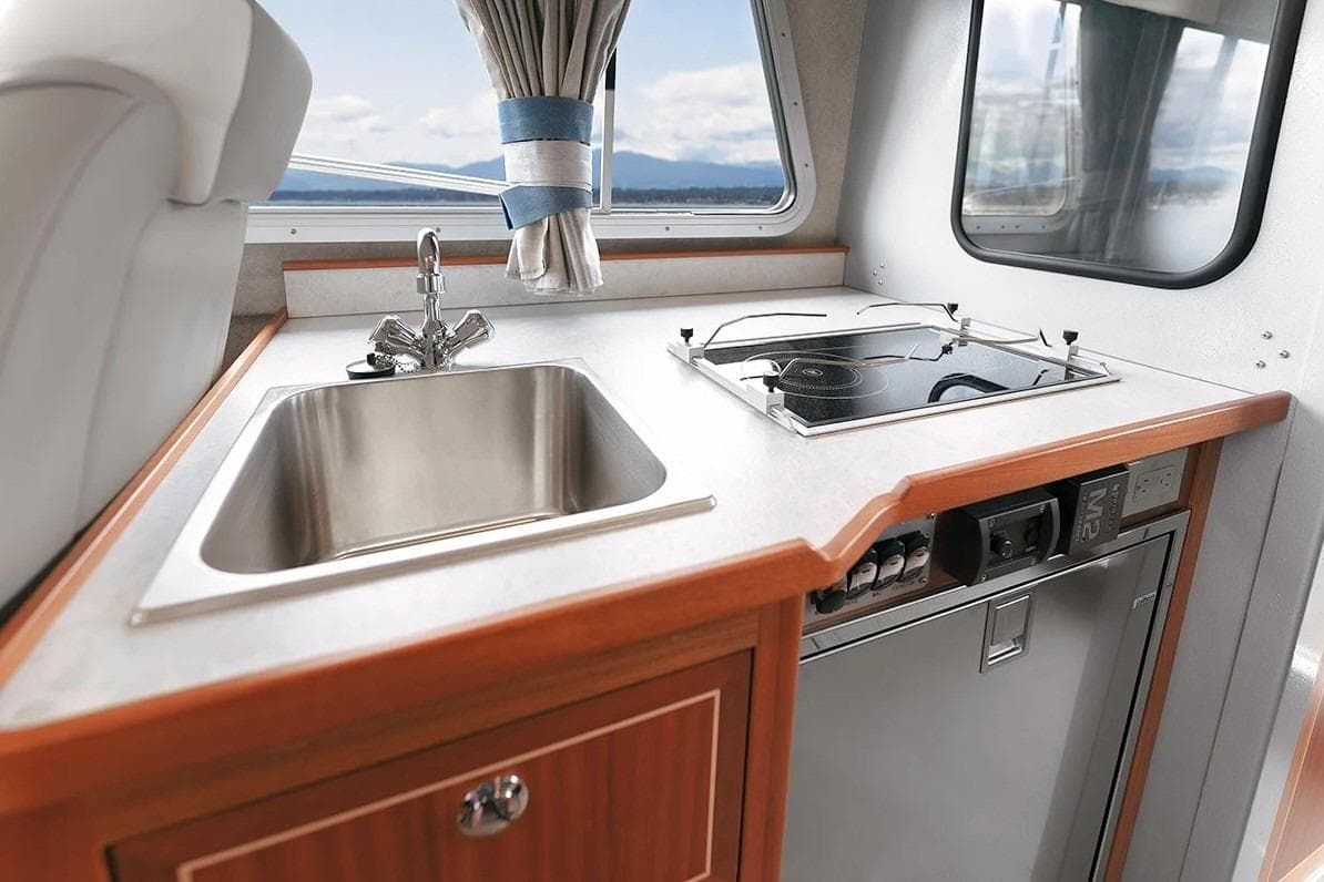 Modern kitchen area in 2026 KingFisher 3225 GFX Offshore boat with sink and stove.