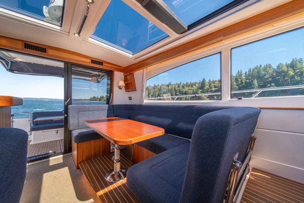 Interior of 2022 Nimbus 405 Coupé yacht with panoramic windows and elegant seating.