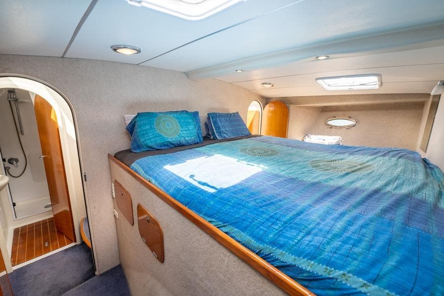 Luxurious cabin interior of 2006 Roger Hill 12 yacht with cozy bed and ensuite bathroom.