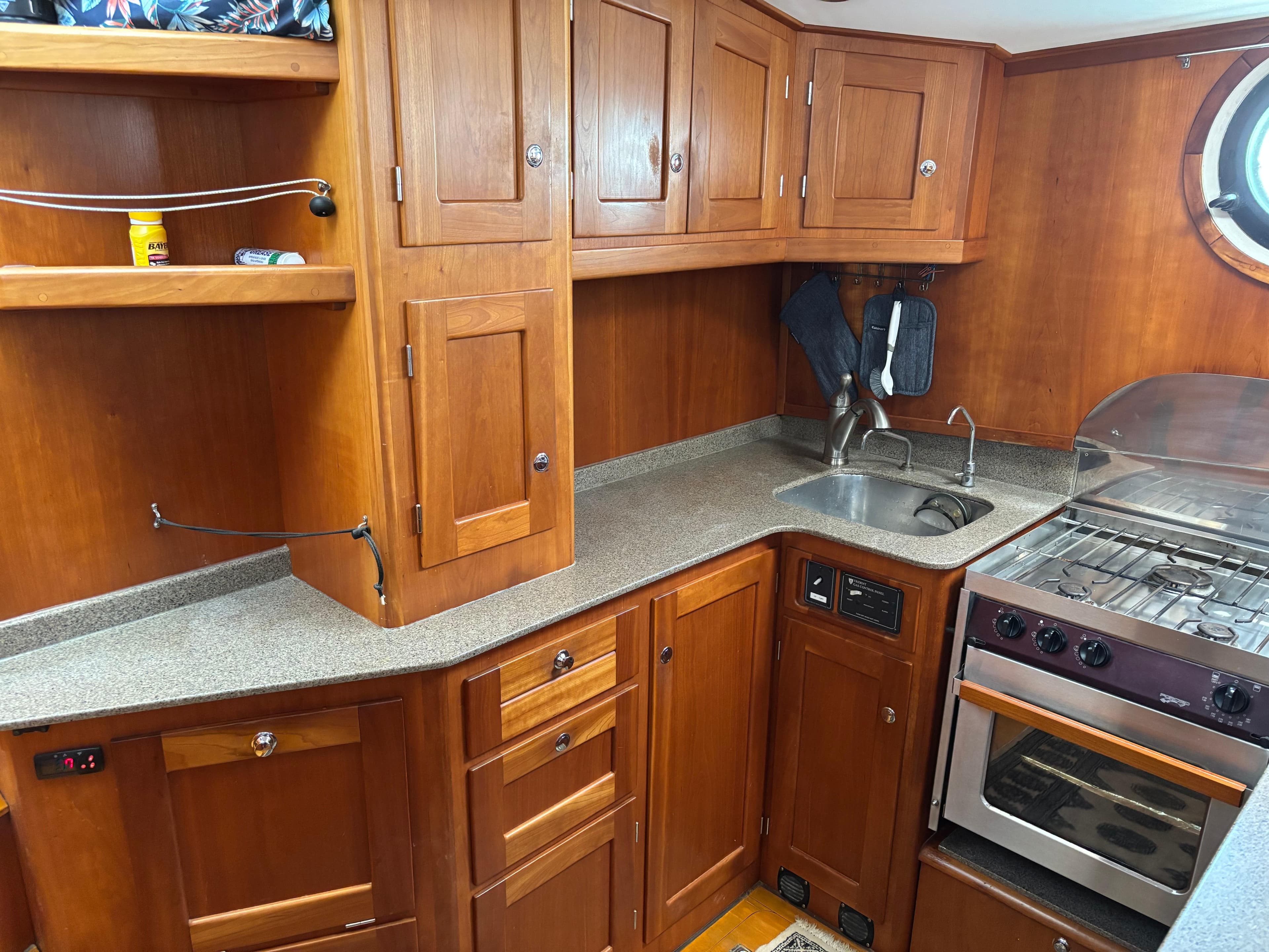 1999 Diesel Duck Trawler kitchen with wooden cabinets, stove, and sink.