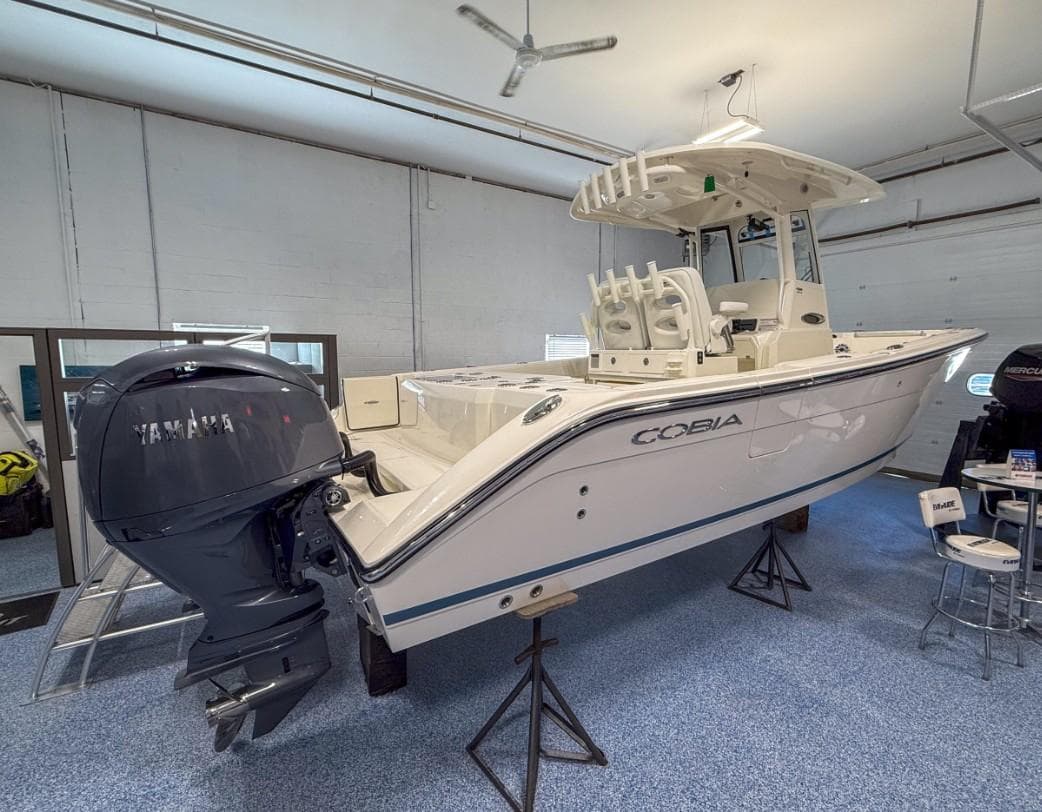 2025 Cobia 265 Open Center Console boat in showroom with Yamaha engine.