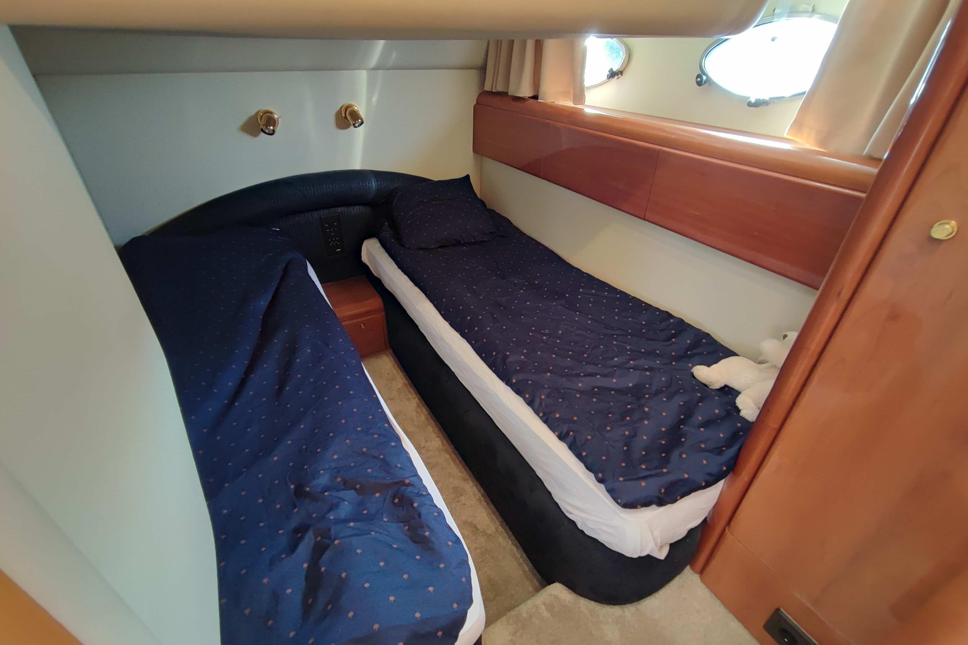 Twin cabin with blue bedding in 1998 Princess V55 yacht interior.