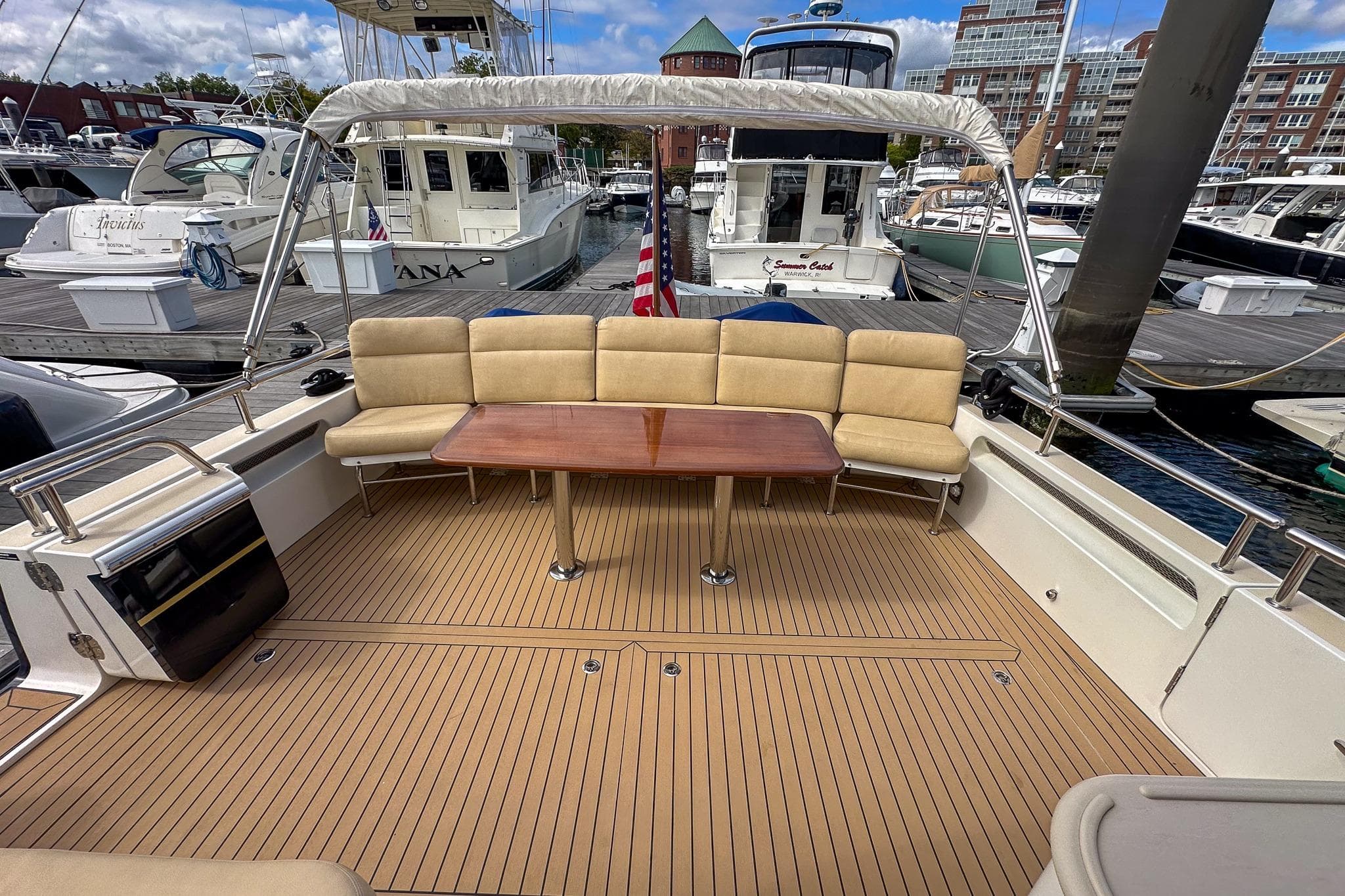 Spacious deck of 2017 MJM 50z yacht with cushioned seating and wooden table.