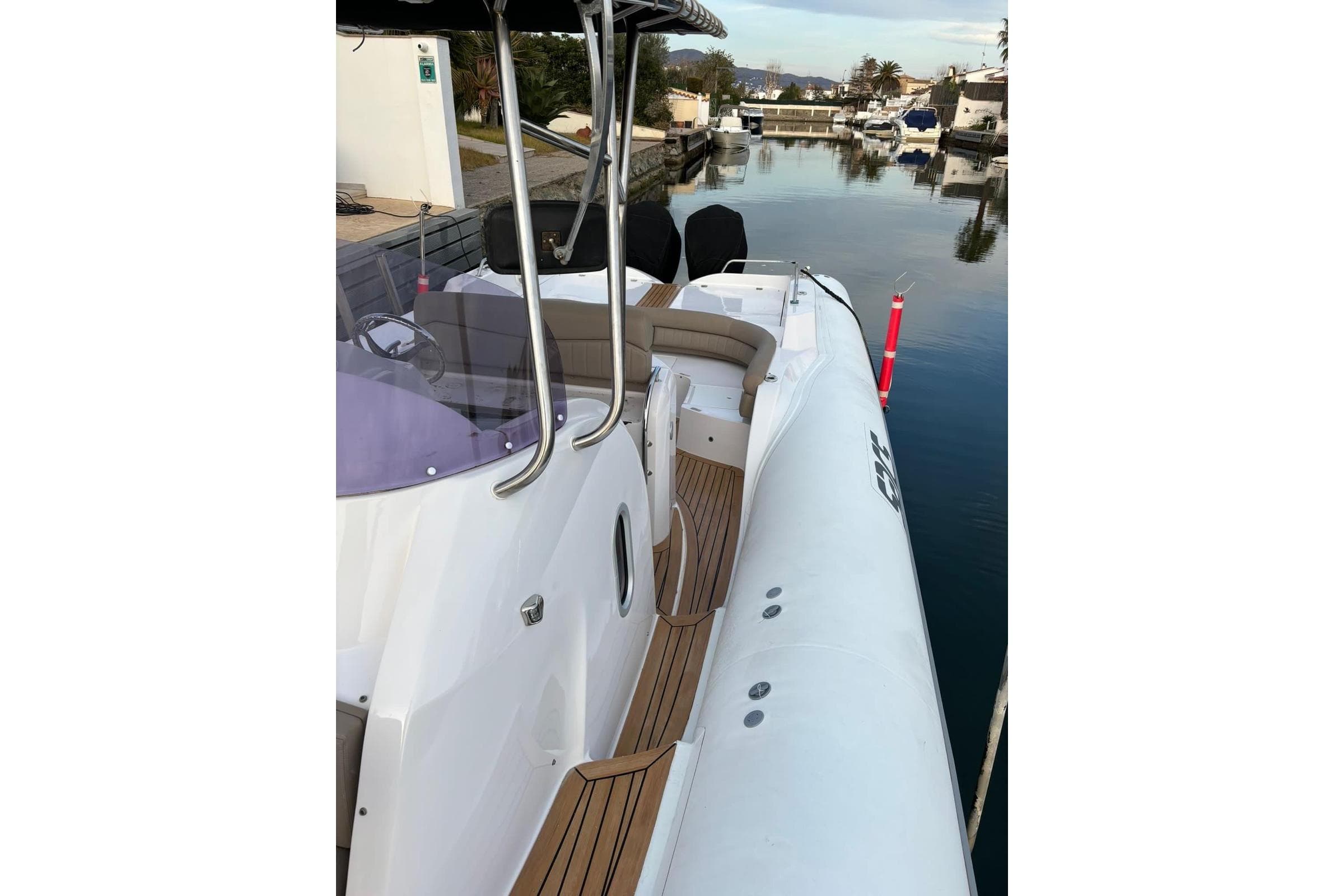 2010 SACS STRATOS boat docked by a calm waterfront, showcasing sleek design and spacious deck.