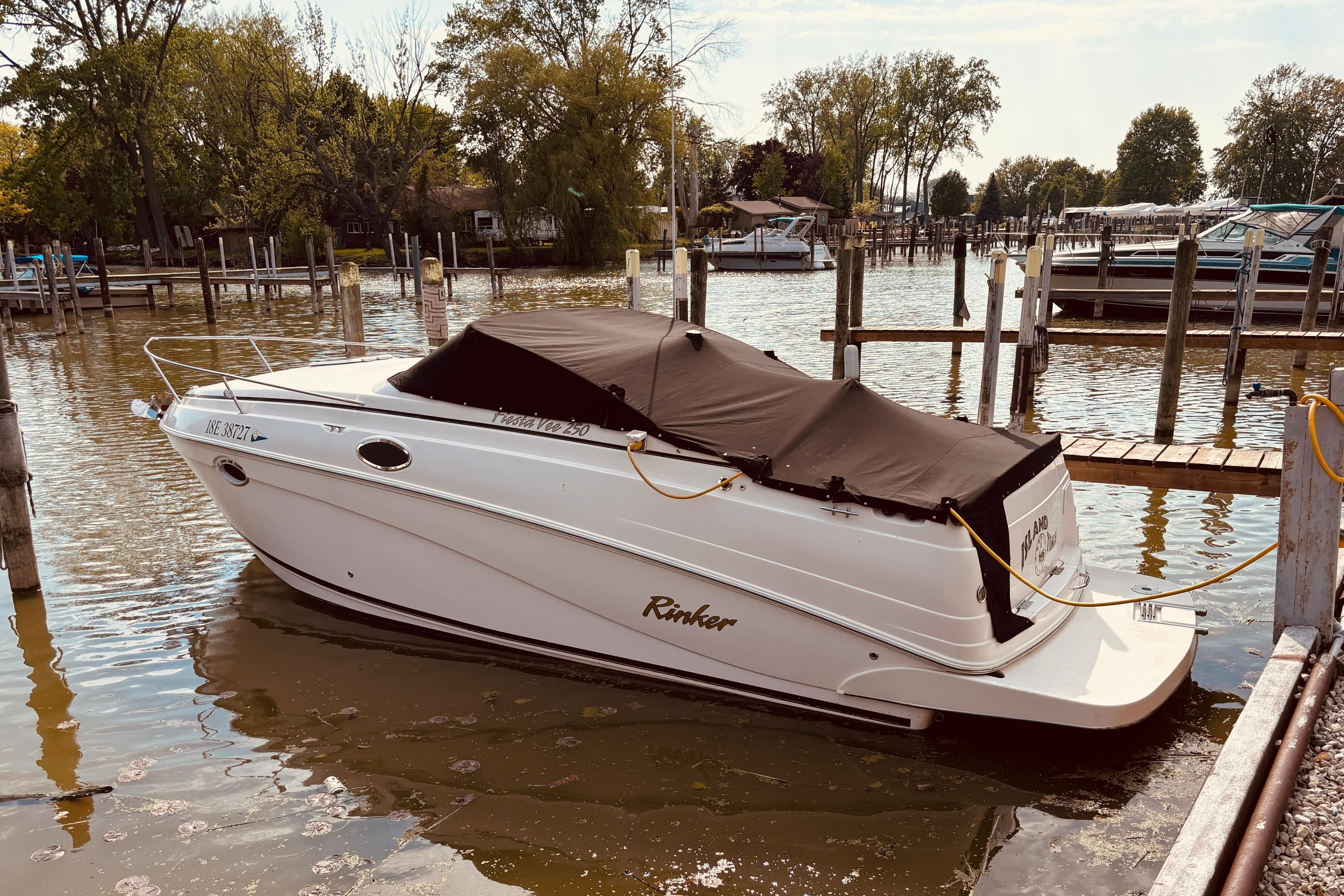 2004 Rinker Fiesta Vee 250 boat docked at a marina with cover.